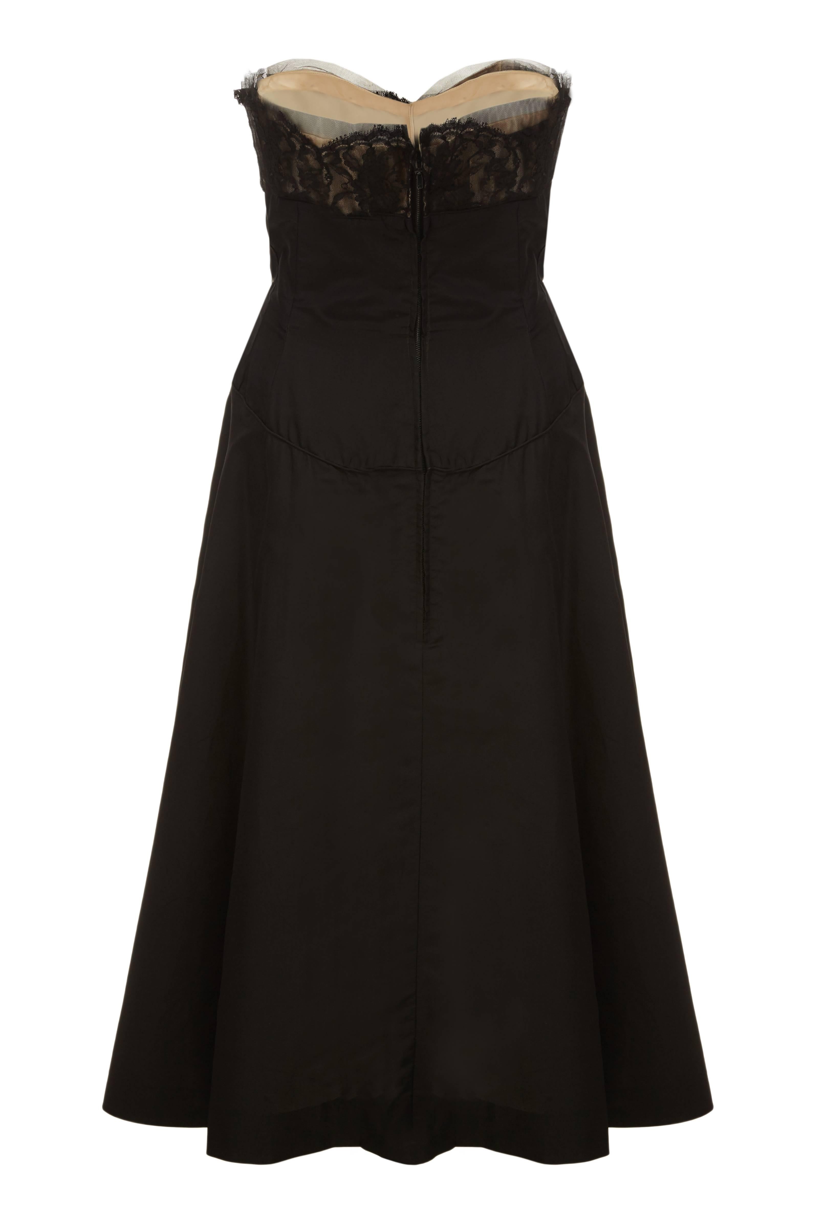 This seductive 1950s black silk satin cocktail dress is of superb quality and construction and in superb vintage condition. The dress features a sweetheart neckline in soft black netting with a nude satin underlay and lace ruffle embellishment over