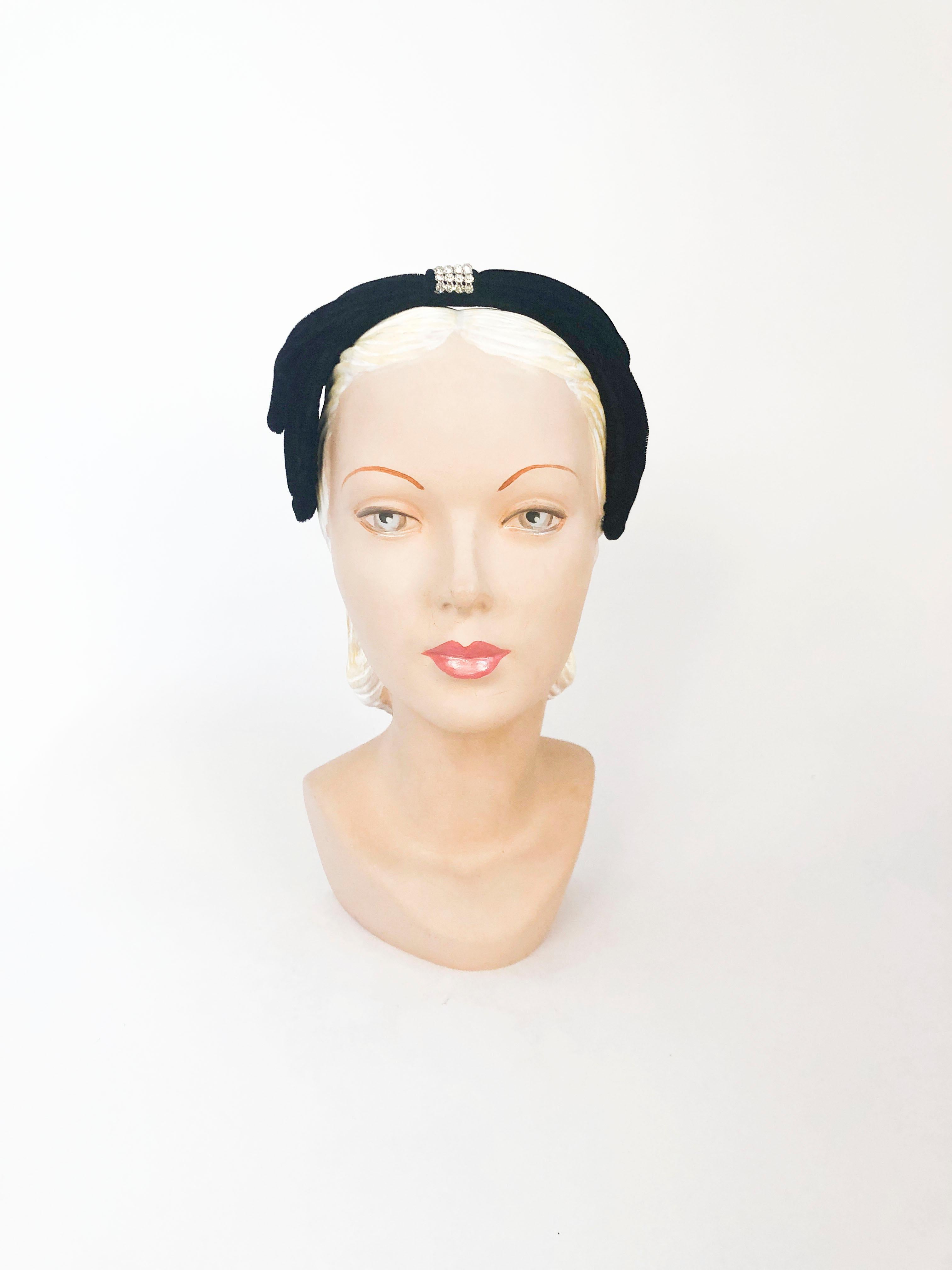 1950's handmade Black cocktail hat made of velvet and decorated with set rhinestone accents on each side and topped with a strip of rhinestone accents to complement the hats bow-like structure.  