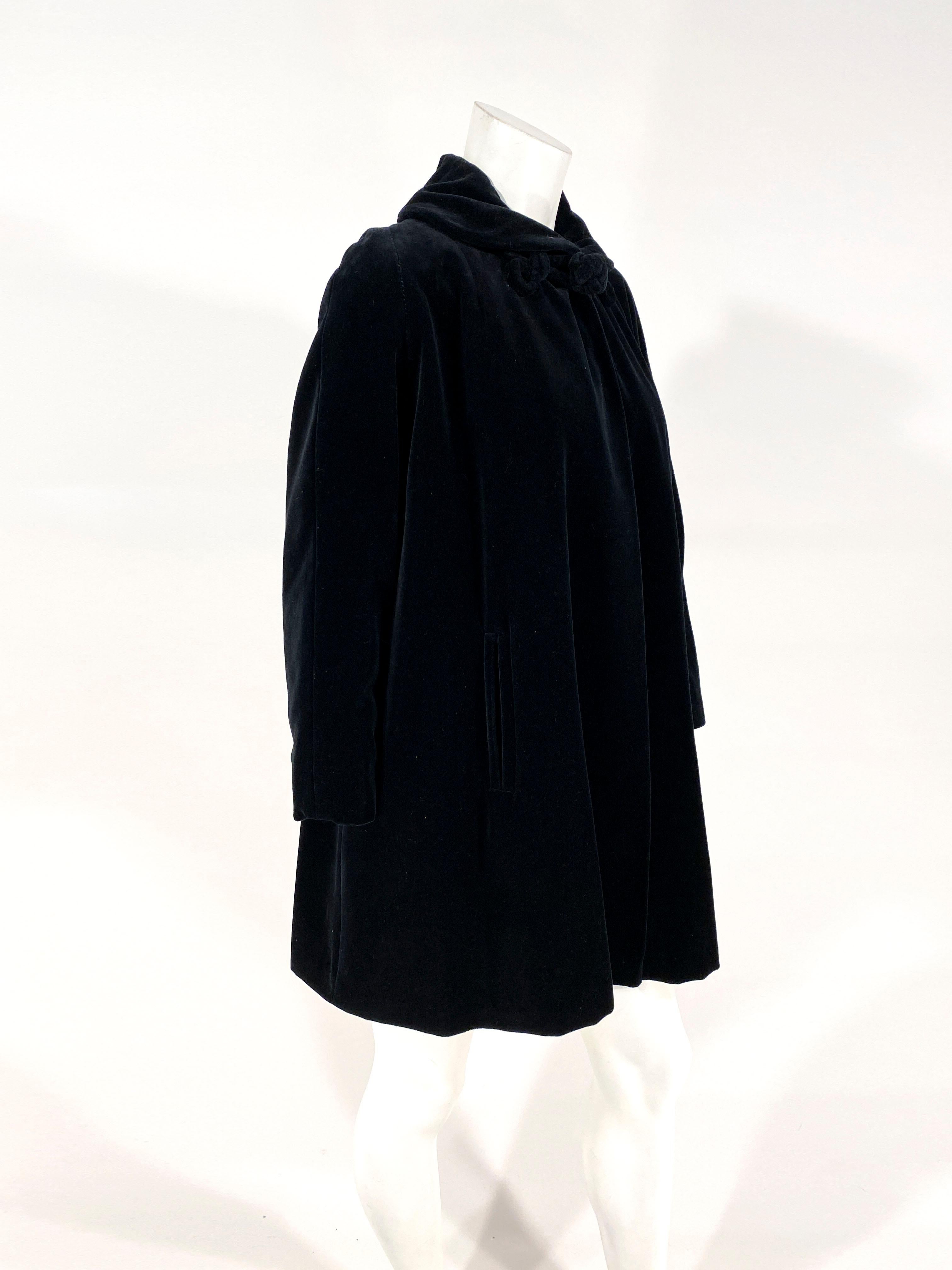 1950s black cotton velvet evening jacket with an A-line shilouette, set-in pockets on both sides, full length sleeves, a peter pan collar and a large handmade corded frog closure on the neckline. The coat is entirely lined in a black twill. 
