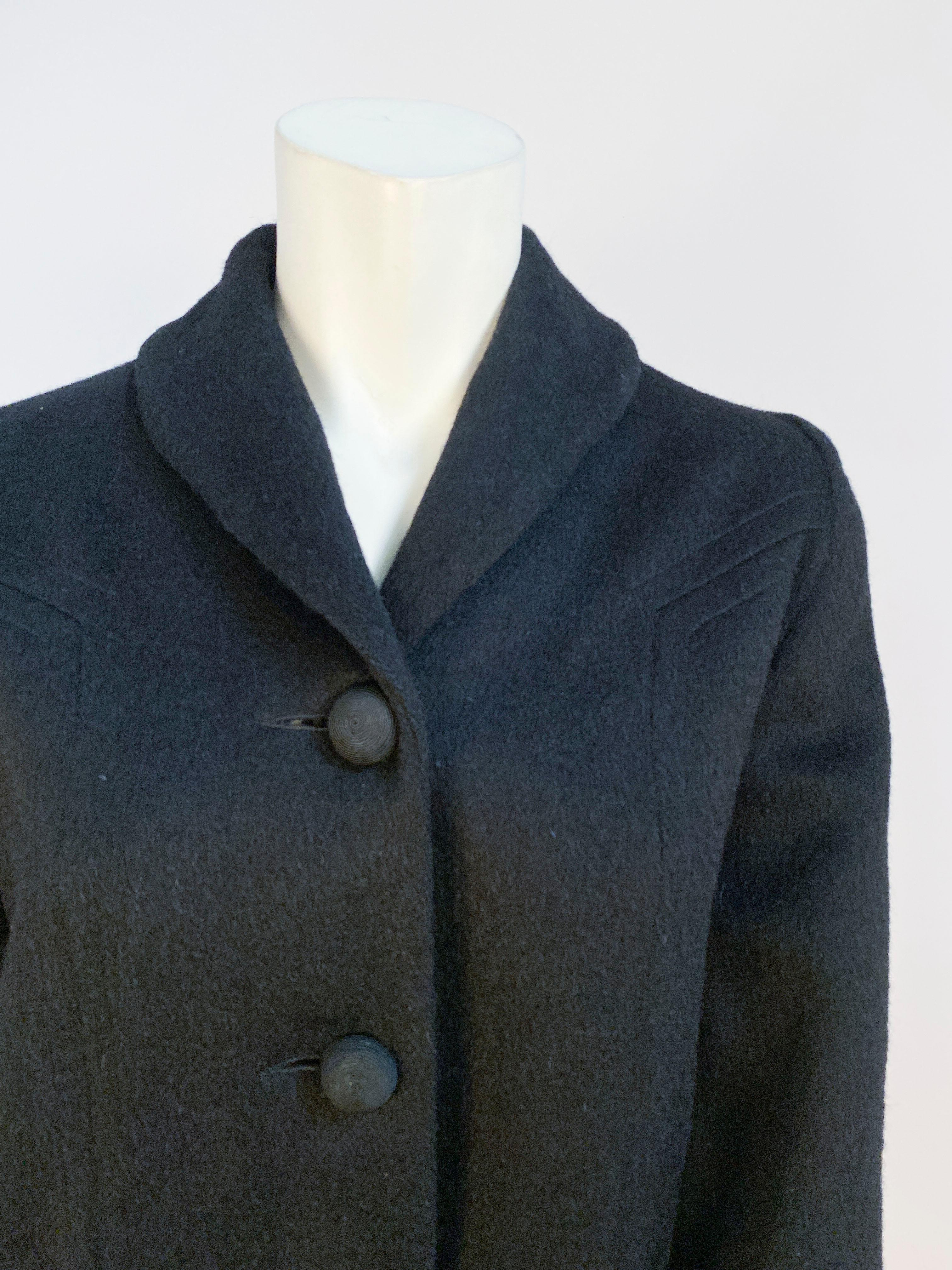 1950s Black wool jacket with full sleeves finished with rolled cuffs. The face of the jacket has in-set panels starting at the shoulder and coming down to the front smile pockets. 