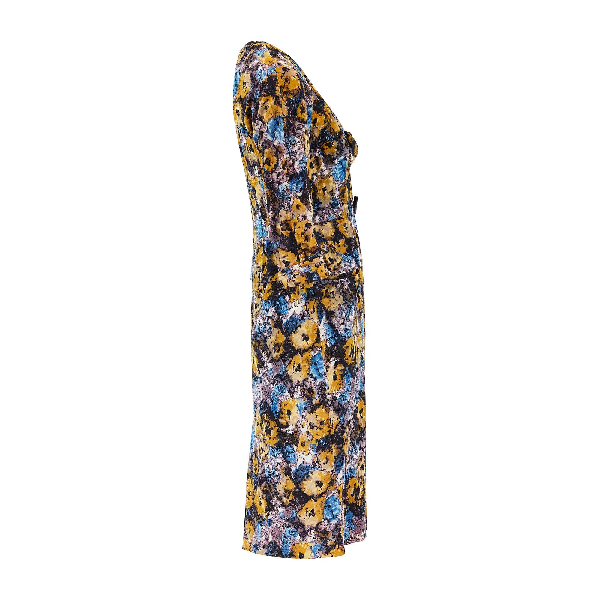 The fabric of this early 1950s floral jersey dress suit is resplendent with splashy, smudged shades of mustard, cobalt blue, mauve, black and white. The dress is tailored to a short-sleeve, tea style with princess seams and intricate pleating to the