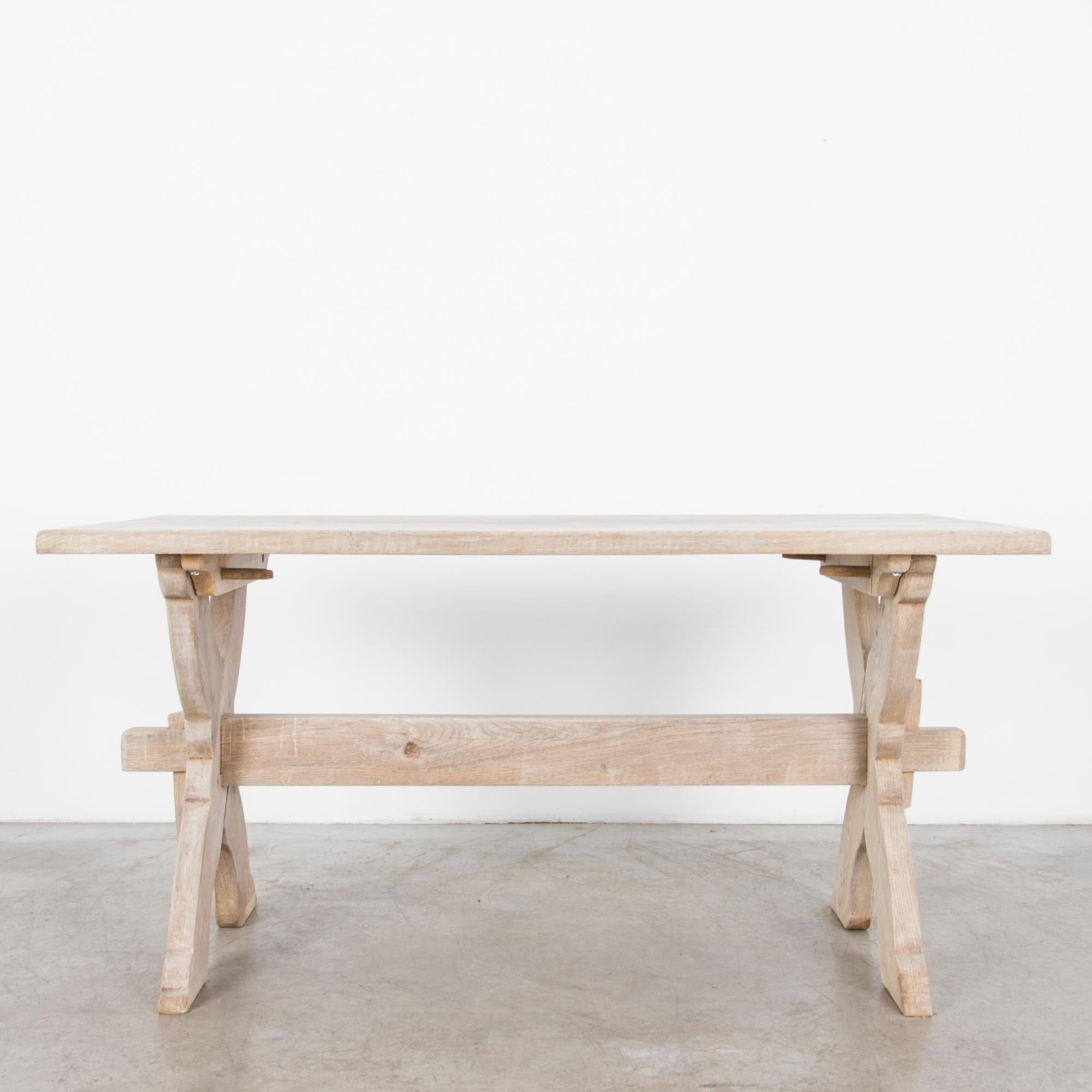 Rustic and simple Belgian style farmhouse table from the 1950s in bleached
oak, features distinct crossed legs and trestle brace. Simple wooden forms
recall the countryside ideal, following the lineage of European craftsmanship, with modernist