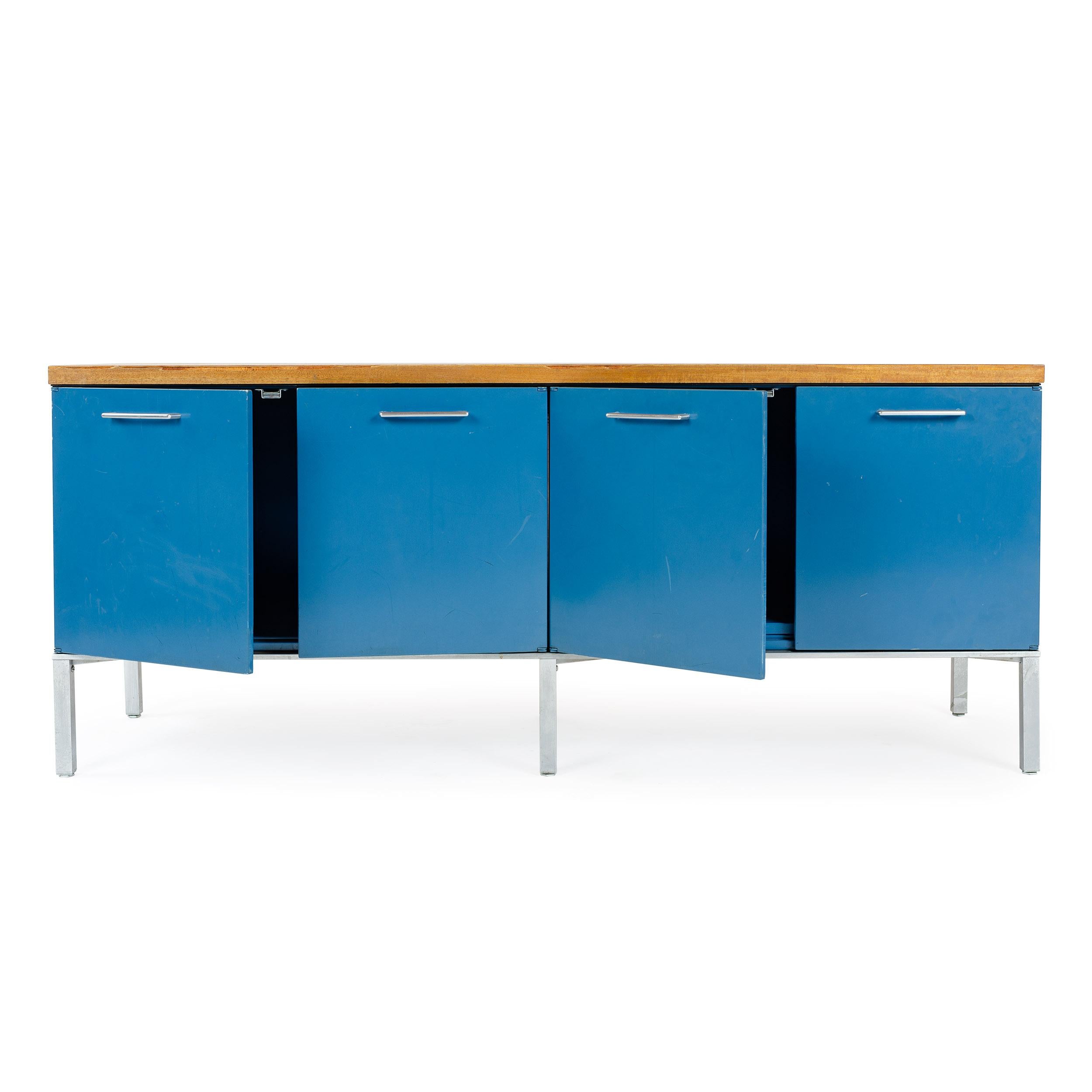An original brilliant blue four door steel credenza with walnut veneered top, square chrome legs, and accenting bright chrome door pulls. Manufactured by GF / General Fireproofing Co. Unsigned.
