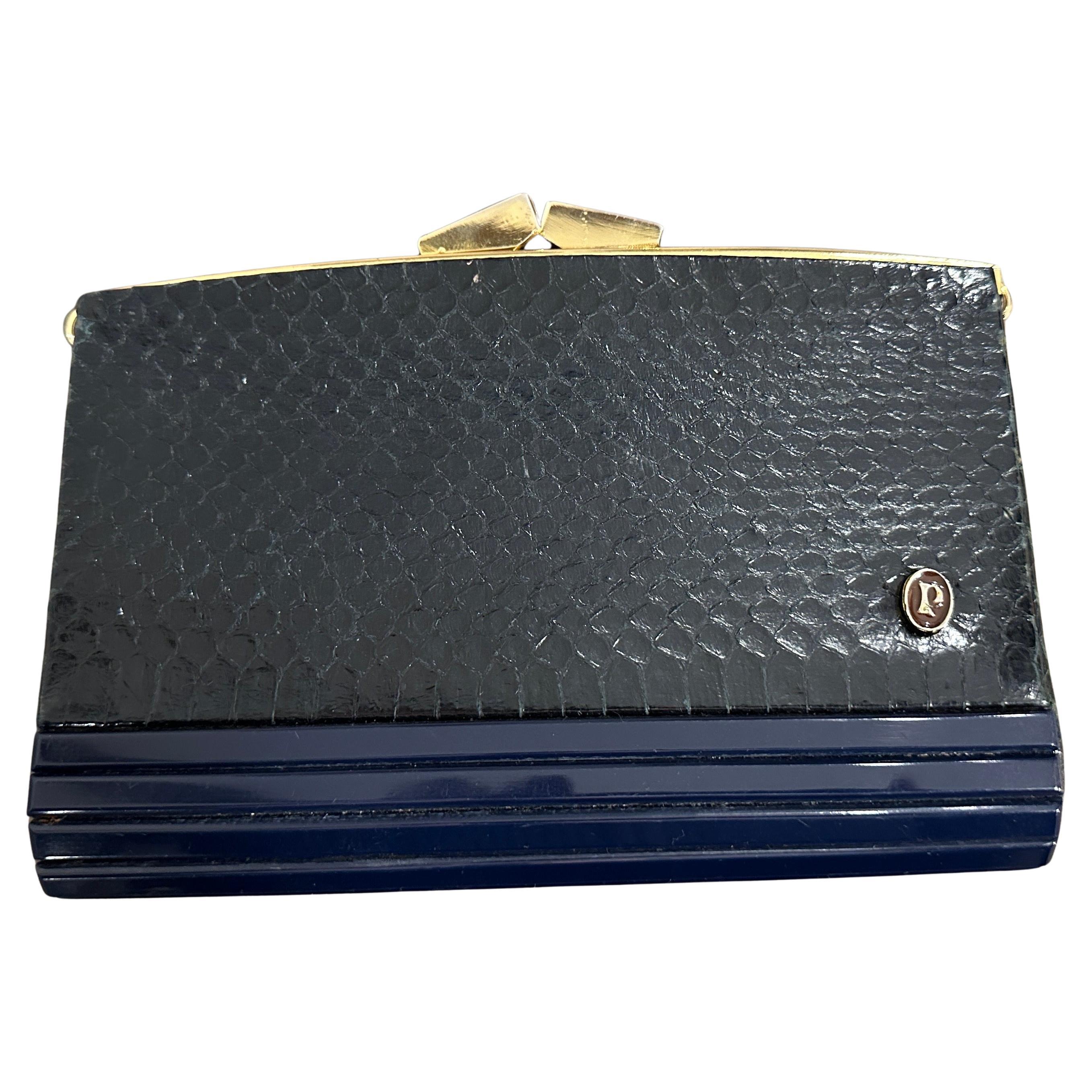 Ce sac du soir italien des années 1950 est un mélange sophistiqué de matériaux et de textures, avec de la bakélite d'un bleu profond et du cuir bleu luxueux avec un motif de peau de serpent gaufré. La silhouette rectangulaire structurée est