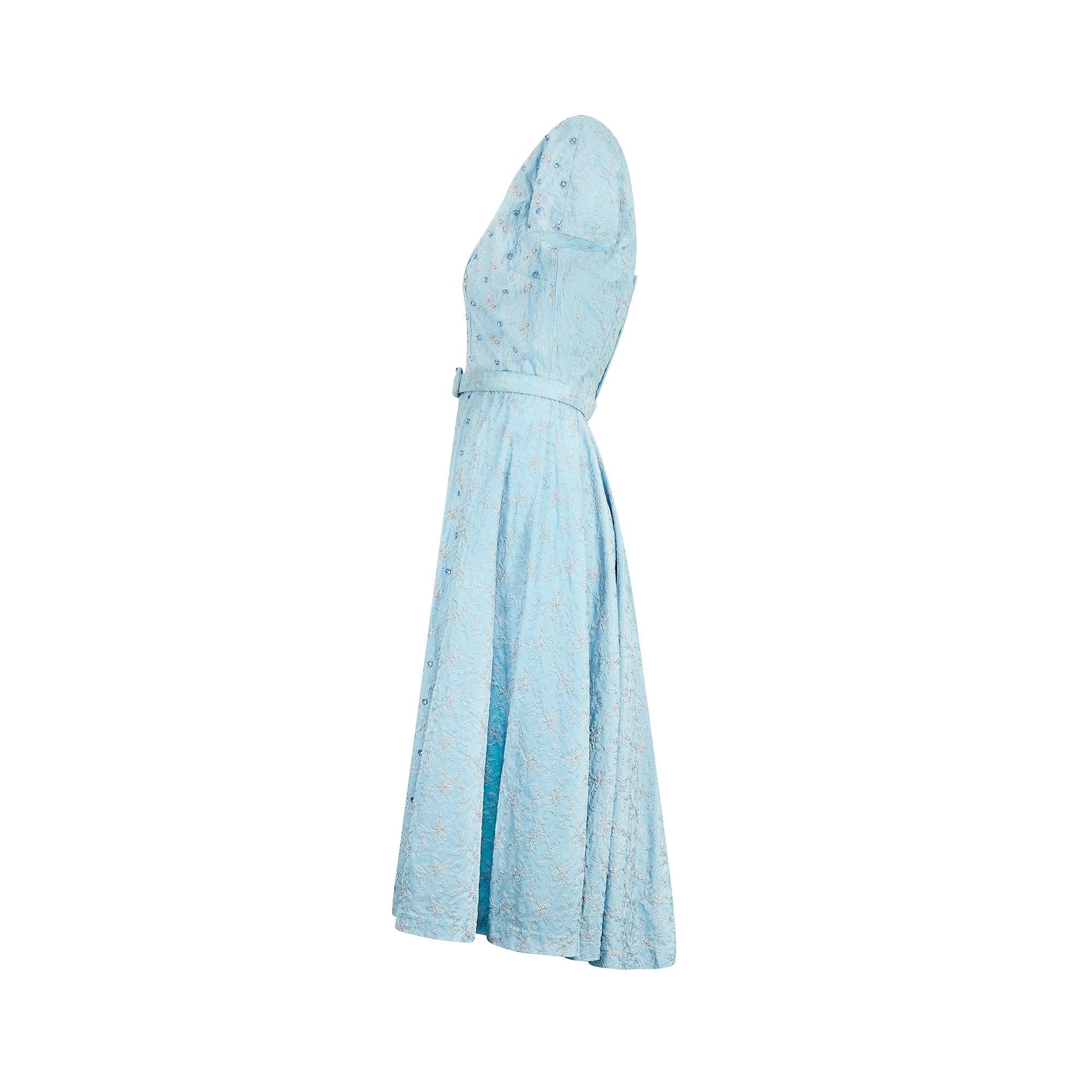 Dieses prächtig verzierte Kleid wurde in den 1950er Jahren entworfen und höchstwahrscheinlich für ein besonderes Ereignis maßgefertigt. Mit seinen kurzen Ärmeln, dem quadratischen Ausschnitt und dem kreisrunden Rock weist es viele Merkmale der