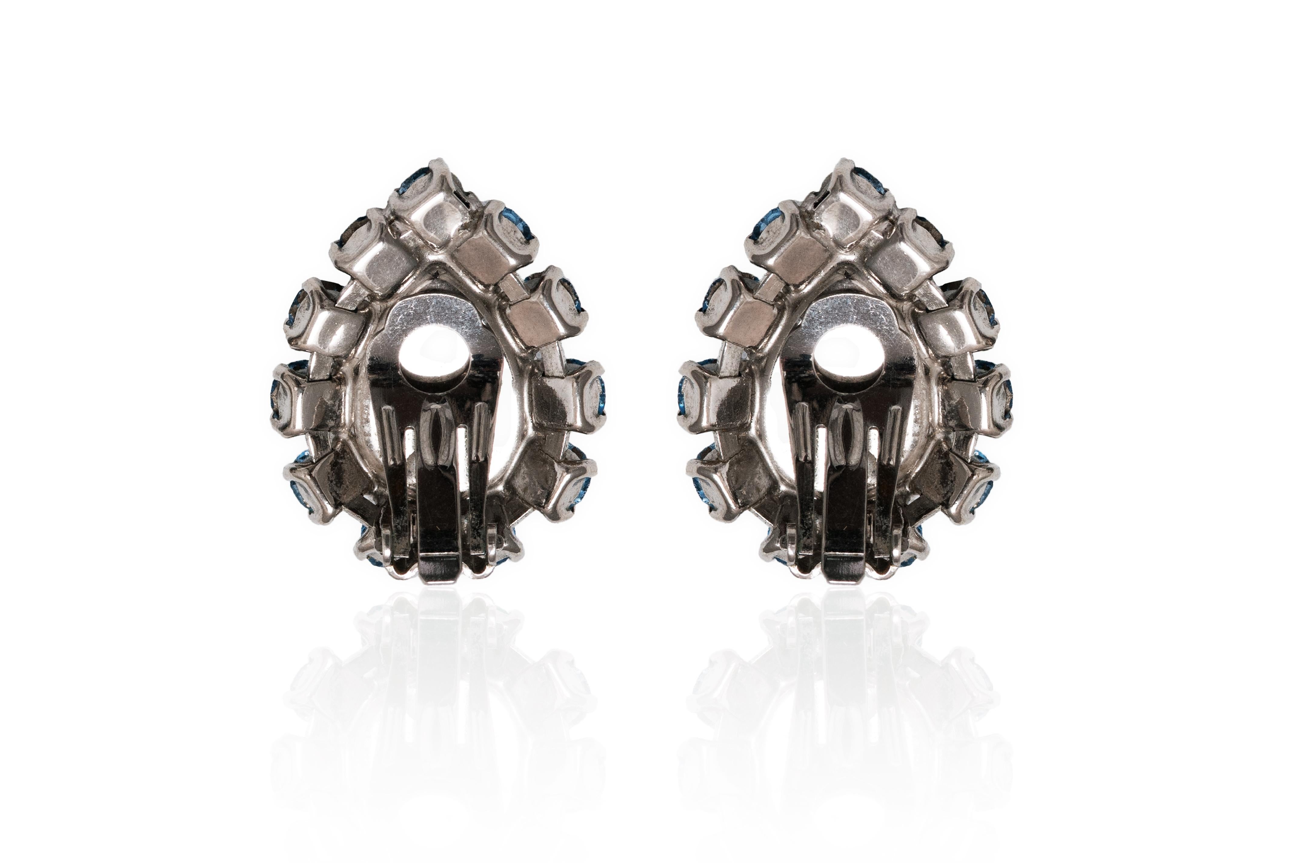 Une très jolie paire de boucles d'oreilles à clip originales des années 1950 dans les plus beaux tons bleus vifs. Chaque boucle d'oreille prend la forme d'une feuille unique en verre bleu, entourée de pierres diamantées en serti clos d'un bleu plus