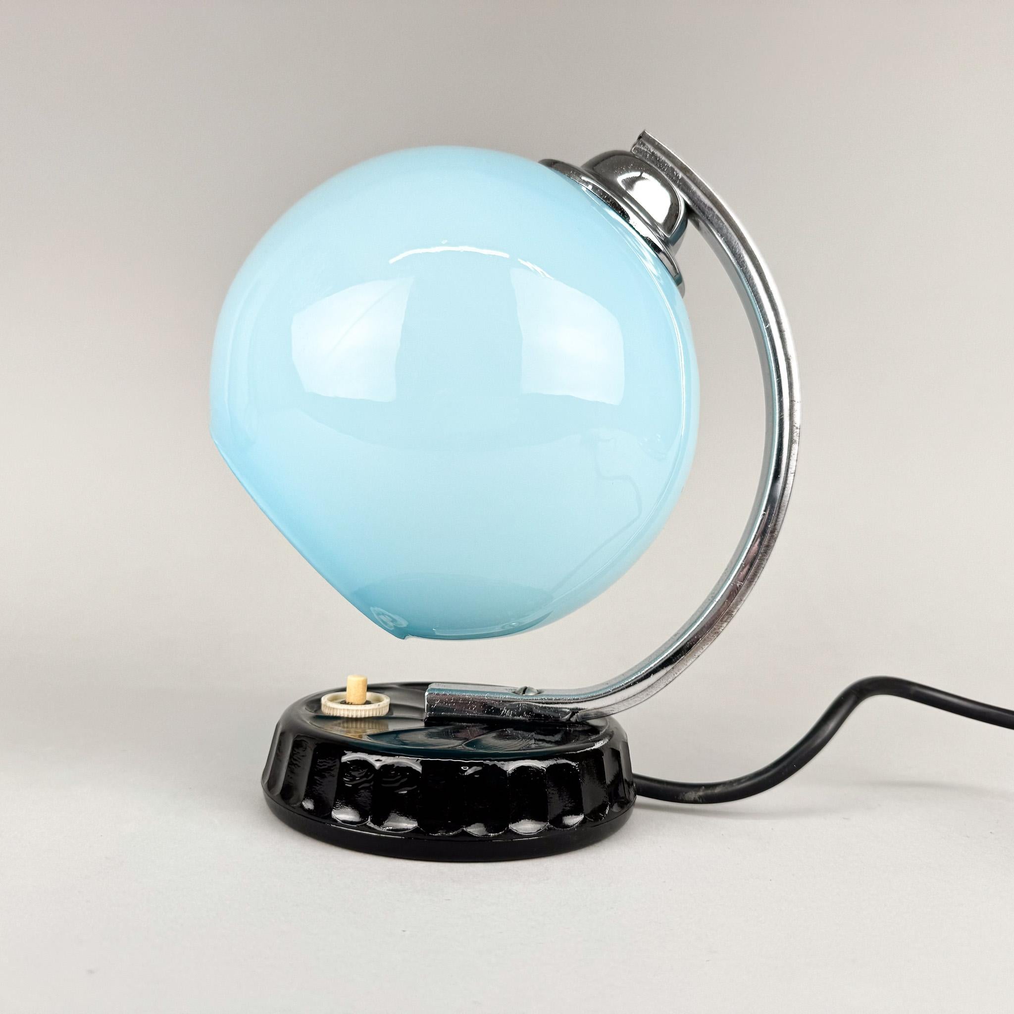 Petite lampe de chevet en chrome, verre opalin bleu et céramique. Produit dans l'ancienne Tchécoslovaquie dans les années 1950. 
Ampoule : 1 x E27 (E26). Adaptateur américain inclus.