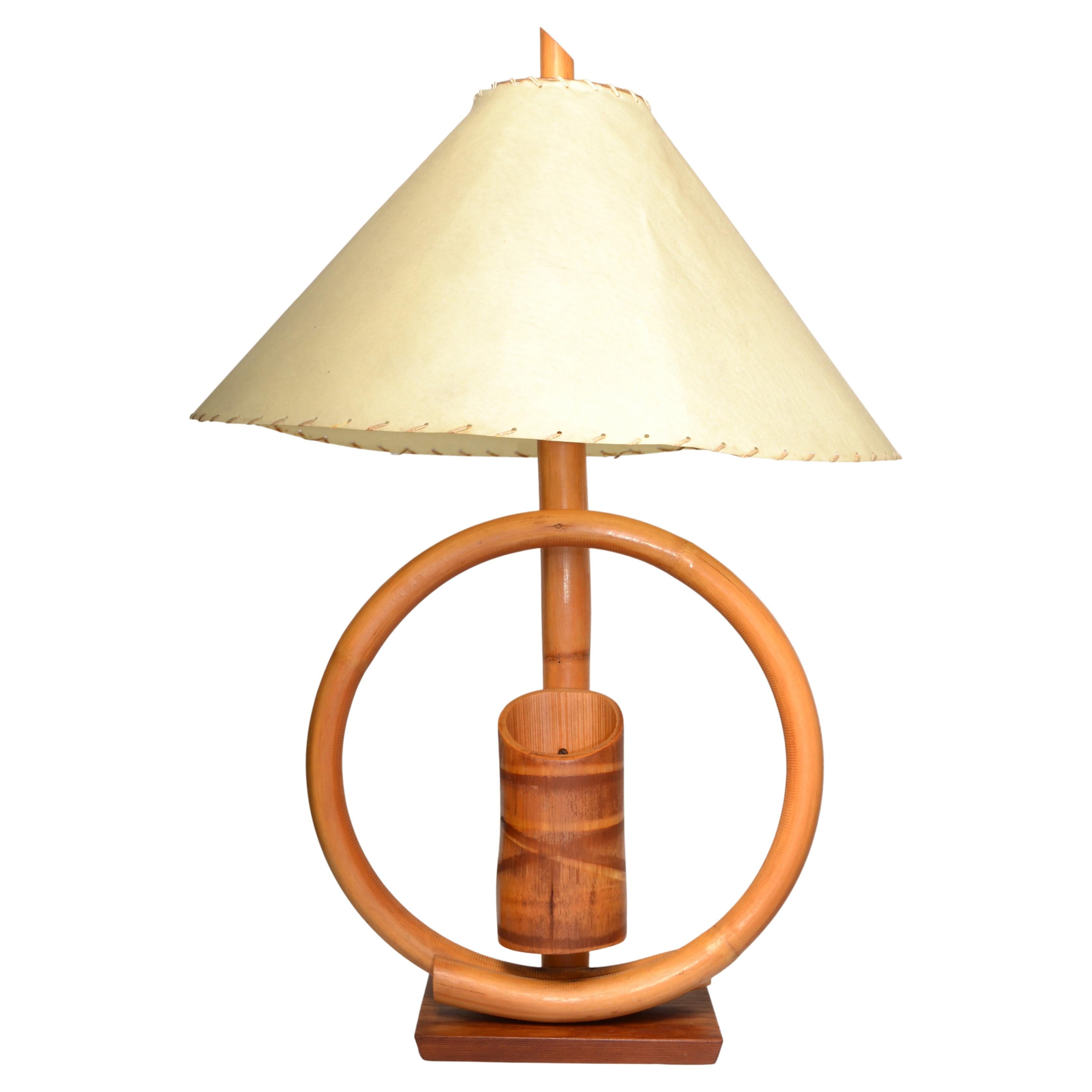 Boho Chic Coastal style bent Bamboo and Caning wrap Table Lamp with original hand-crafted Goatskin Shade. This rare Mid-Century Modern Lamp features one bent circle Bamboo arm with Pencil Holder in the Center and mounted on a dark rectangle