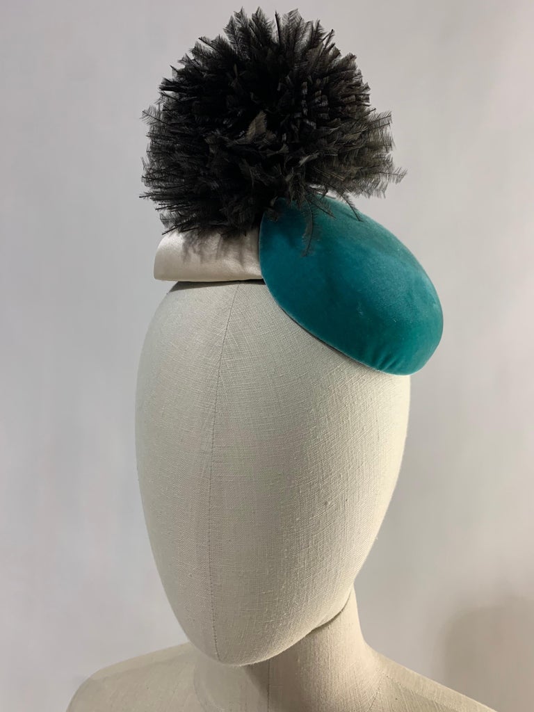 1950s Bonwit Teller Avant Garde toy hat in turquoise velvet and ivory satin structured discs with black ostrich feather pouf. Combs to secure at the proper angle. Be the most fabulous show pony in this charming fascinator. One size fits all. 
