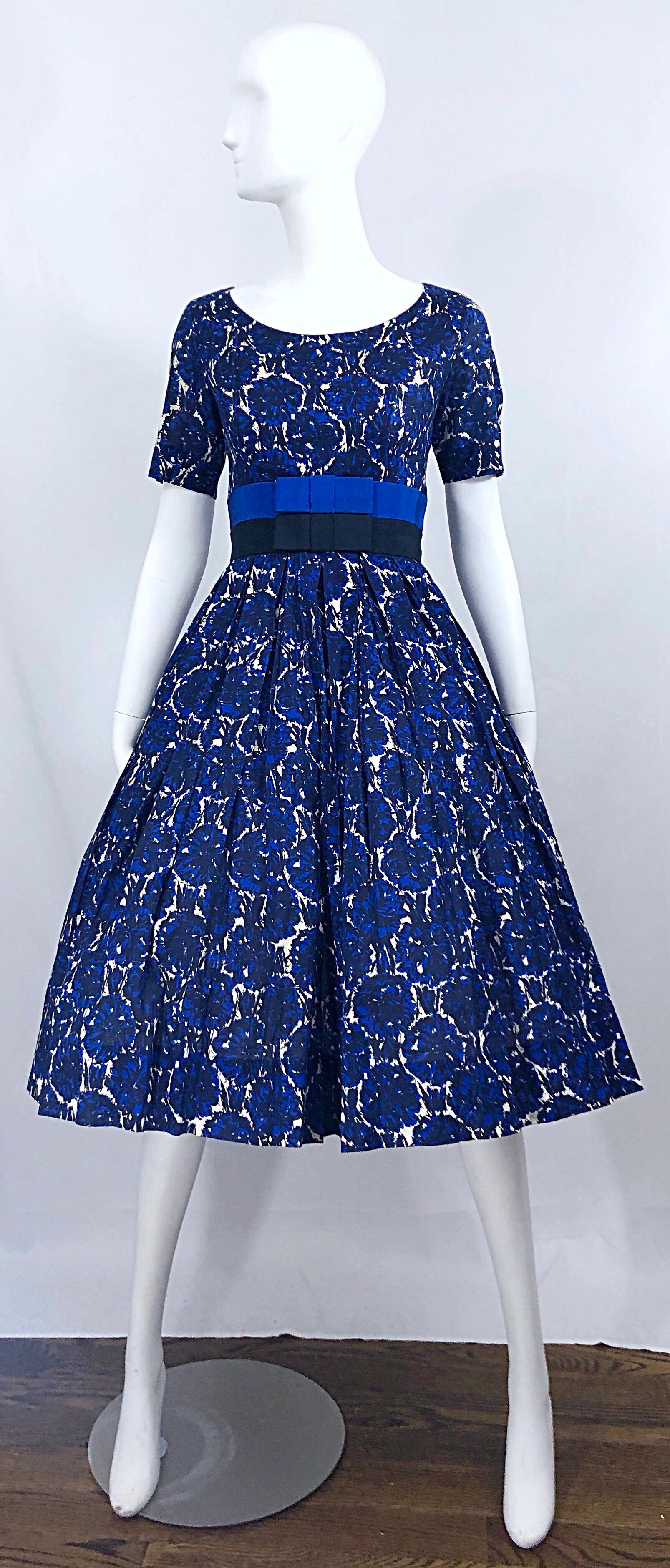 Phenomenal vintage 50s BONWIT TELLER demi couture blue abstract flower print fit n' flare cotton dress! Features a fitted bodice, with two bands of silk grosgrain bows in blue and black. Full skirt has plenty of room to accomodate a crinoline for