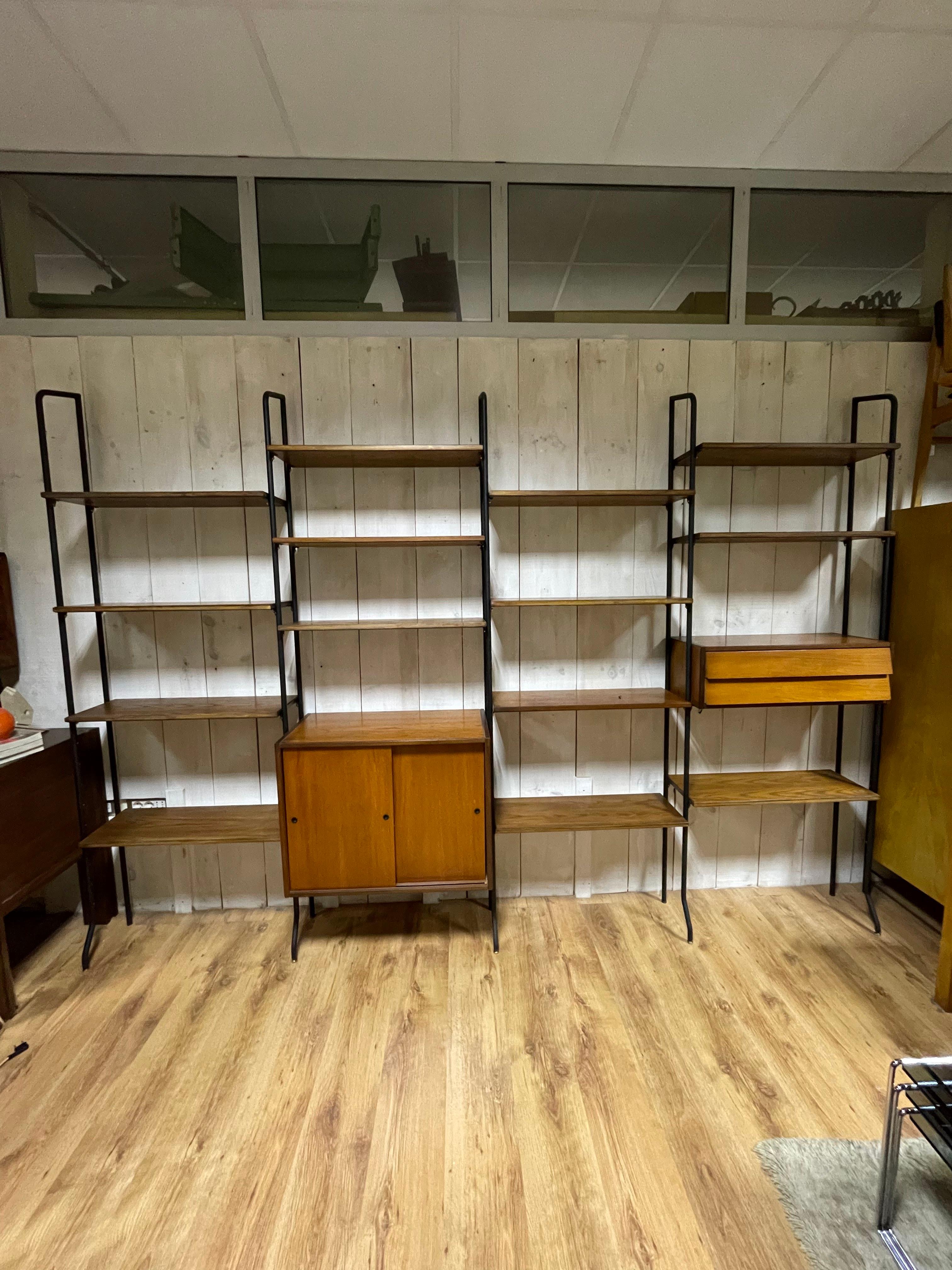 1950s Bookcase by Studio Amma Turin.
It is made up of 4 spans with iron uprights with brass feet, 14 shelves, a closed container space with sliding doors and one with two drawers.
The two storage spaces can be positioned however you prefer.

The