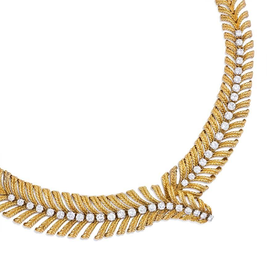 A gold and diamond necklace of stylized plume design with a tapered bypass central motif, in 18k and platinum.  Atw. 6.00 ct. diamonds. Boucheron, Paris