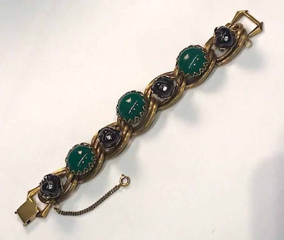 Attributed to West German fashion jewelry company Henkell and Grosse from the 1950. The bracelet has double links in an antique gold tone finish. Three 7/8 of an inch green glass cabochons are set with cut out dog teeth prongs. The four twist molded