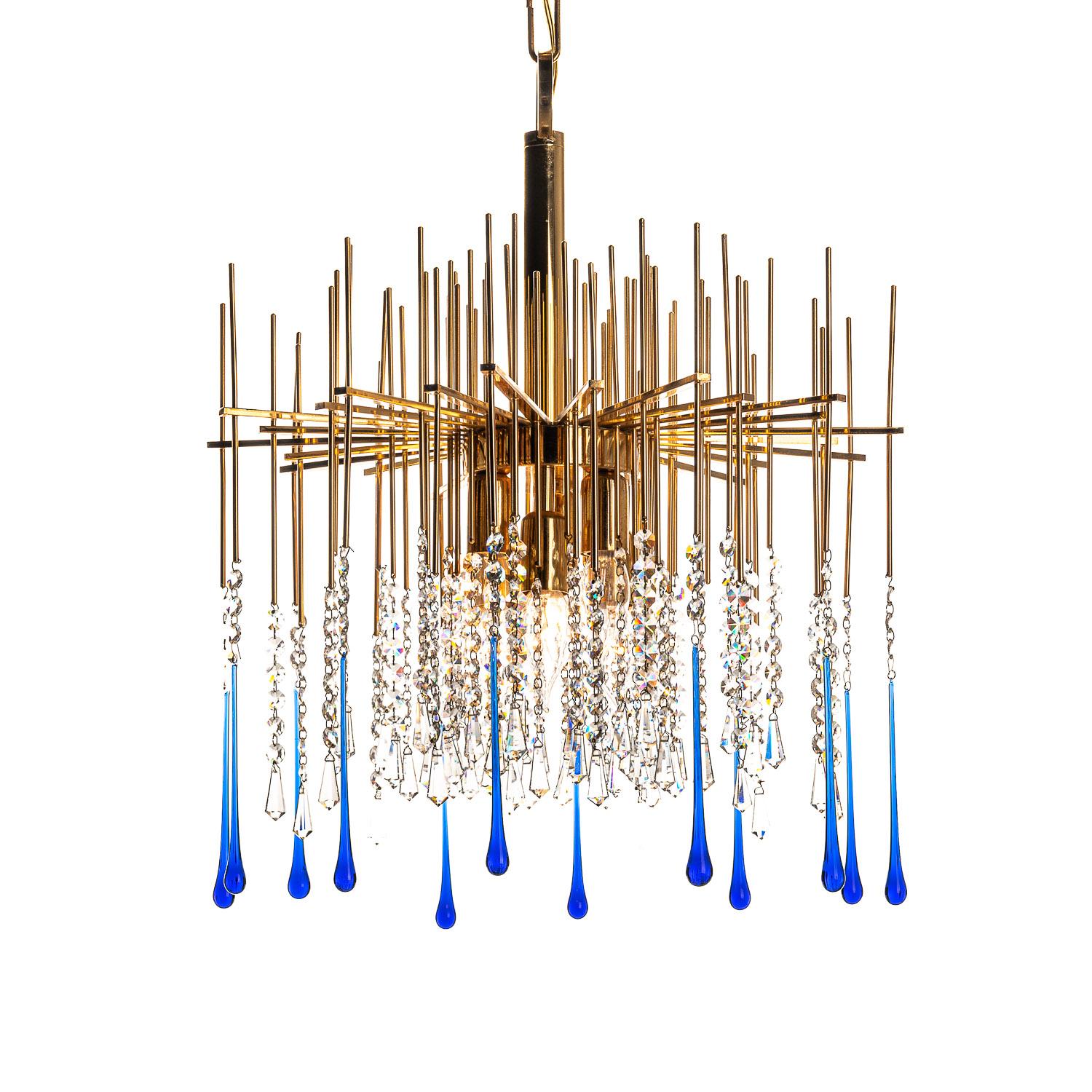 Benvenuto in questo delizioso lampadario degli anni '50, attribuito al designer Palwa. Le aste dritte si irradiano verticalmente e orizzontalmente in una forma ipnotica dalla colonna in ottone, conducendo a lunghe gocce di cristallo blu di varie
