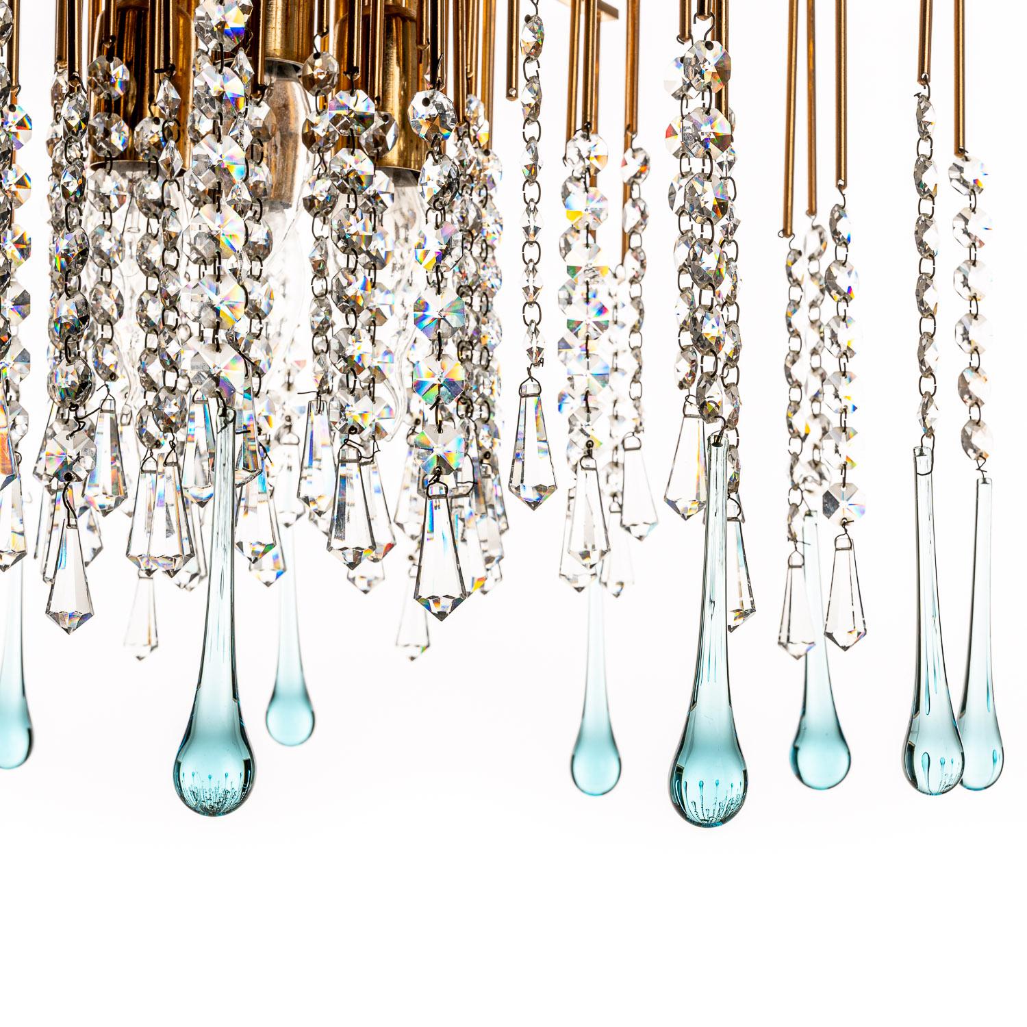 Welcome to this delightful 1950s chandelier, attributed to the designer Palwa. Straight rods radiate vertically and horizontally in a mesmerising form from the brass column, leading to blue-tinted crystal drops of various lengths to create a