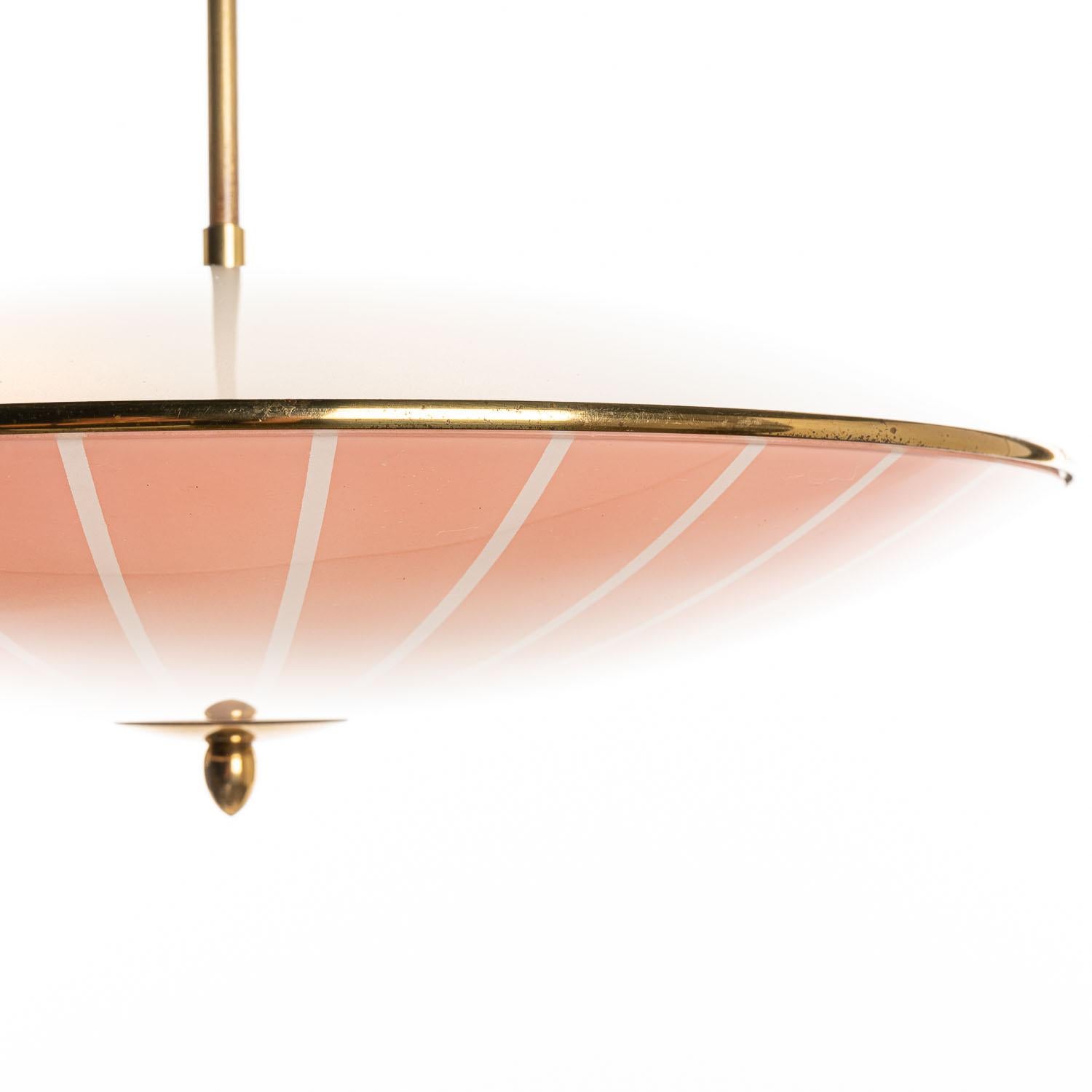 This elegant piece consisting of a brass frame and 2 unique frosted and satin glass reflector/saucers. 
The lower round curved pink-orange-colored glass reflector with white stripe motifs mounts below a round white satin glass reflector. Finished