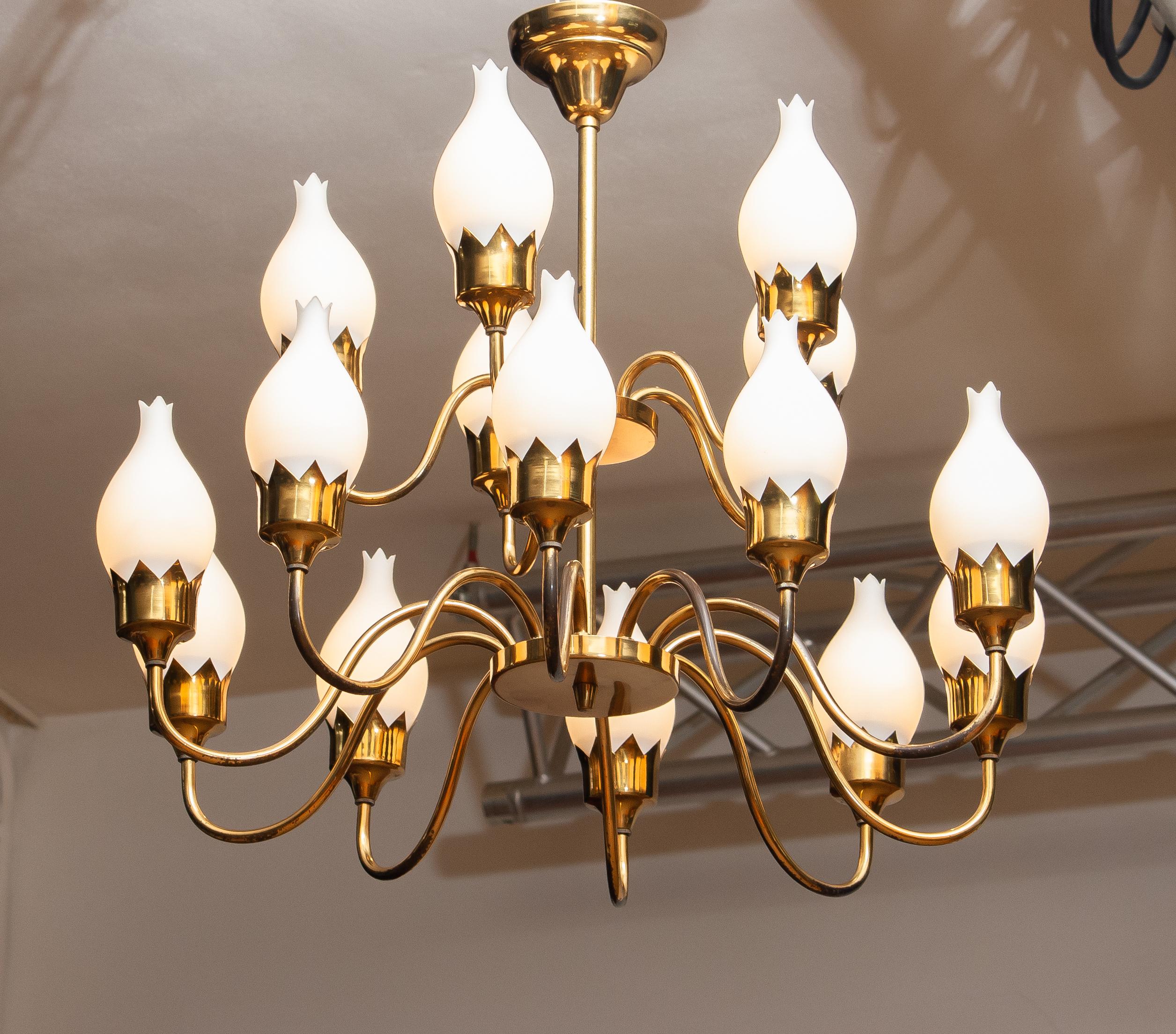 Beautiful gold colored / brass arm chandelier with fifteen arms and white glass / opaline tulips all in original condition by Fog & Mørup, Denmark, 1950s.
Technically 100% with fifteen e27 / E28 sockets which suits 110 and 230 volts.
The overall