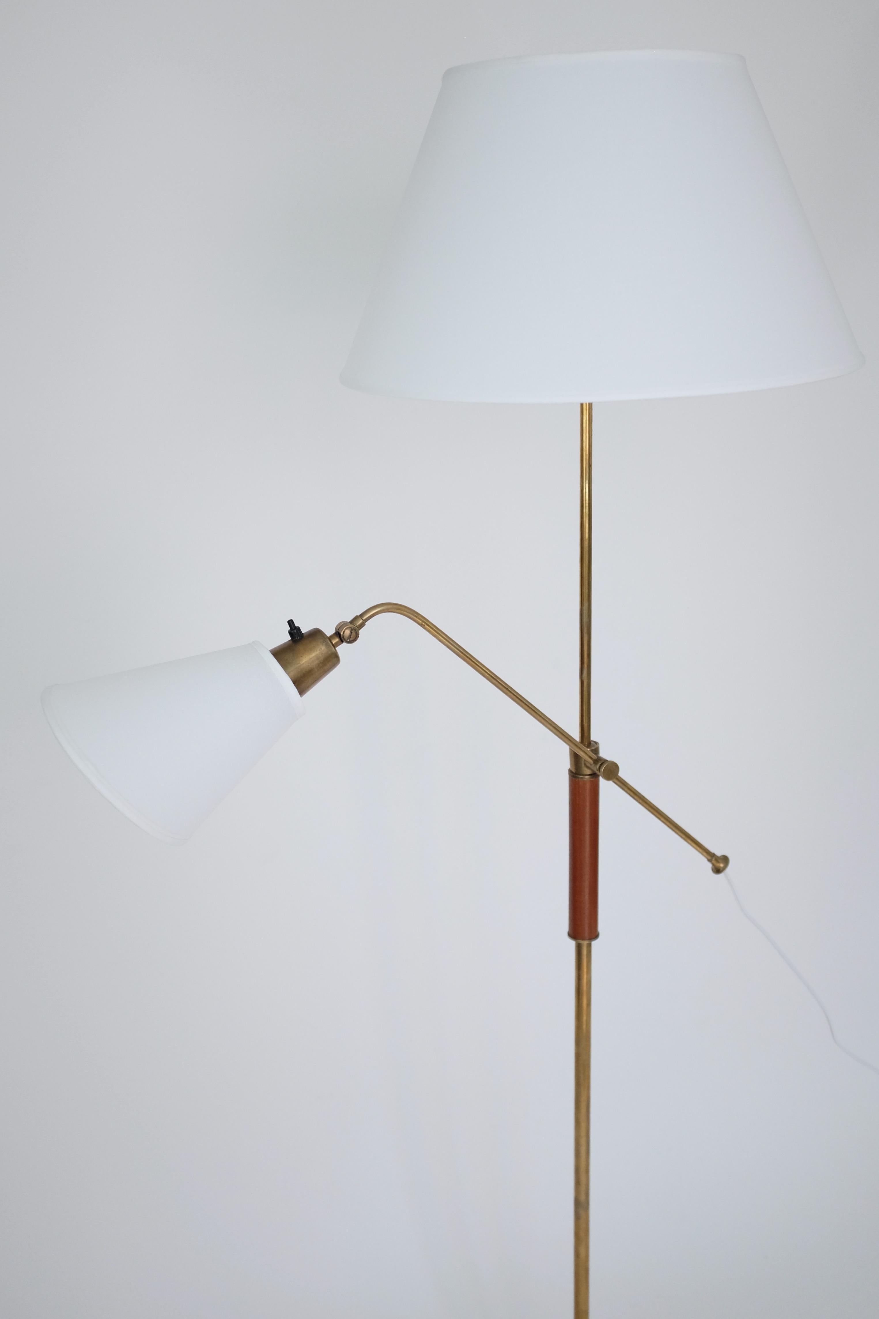Impressive two armed brass and wood floor lamp by Bertil Brisborg for Nordiska Kompaniet. Manufactured in the 1950's where the designer served as Chief Architect for the lighting department for many years. The main lamp can be adjusted in height and
