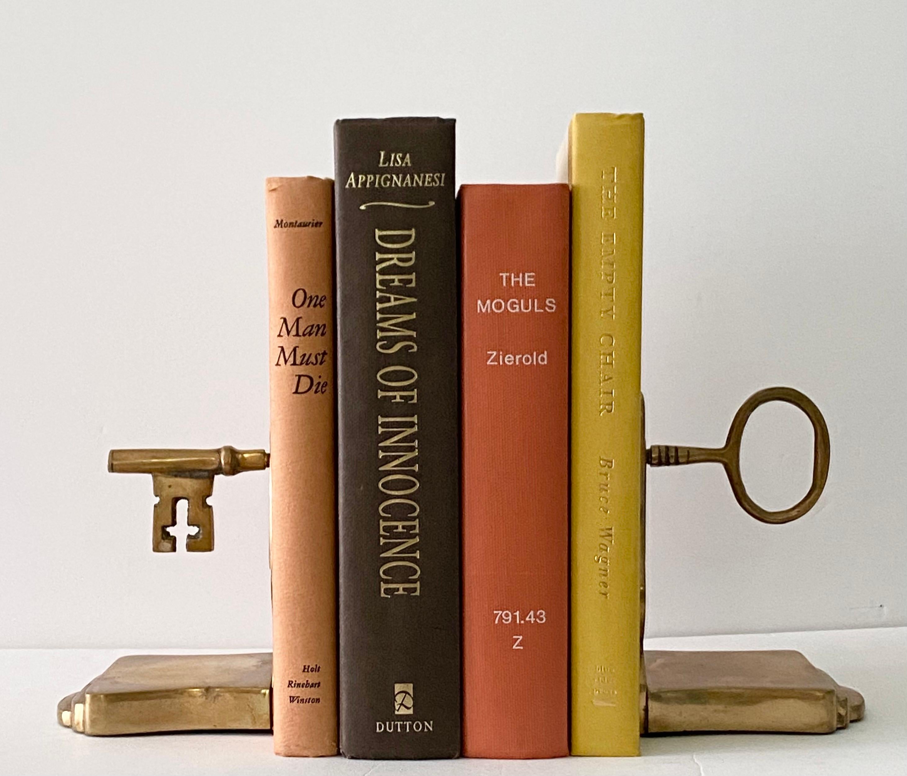 We are very pleased to offer a pair of vintage bookends, circa the 1950s. These solid brass bookends showcase a captivating and nostalgic design, each resembling half of an antique bridge ward key. One bookend boasts the beautifully sculpted bow,