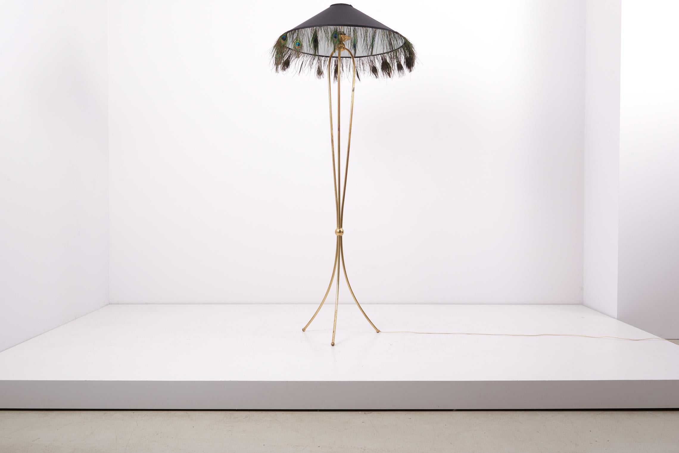 Elegant three-legged floor lamp, made of brass in the 1950s.
Including new custom lamp shade in black chintz with natural peacock feathers.

1 x E27 socket.

Please note: Lamp should be fitted professionally in accordance to local requirements.