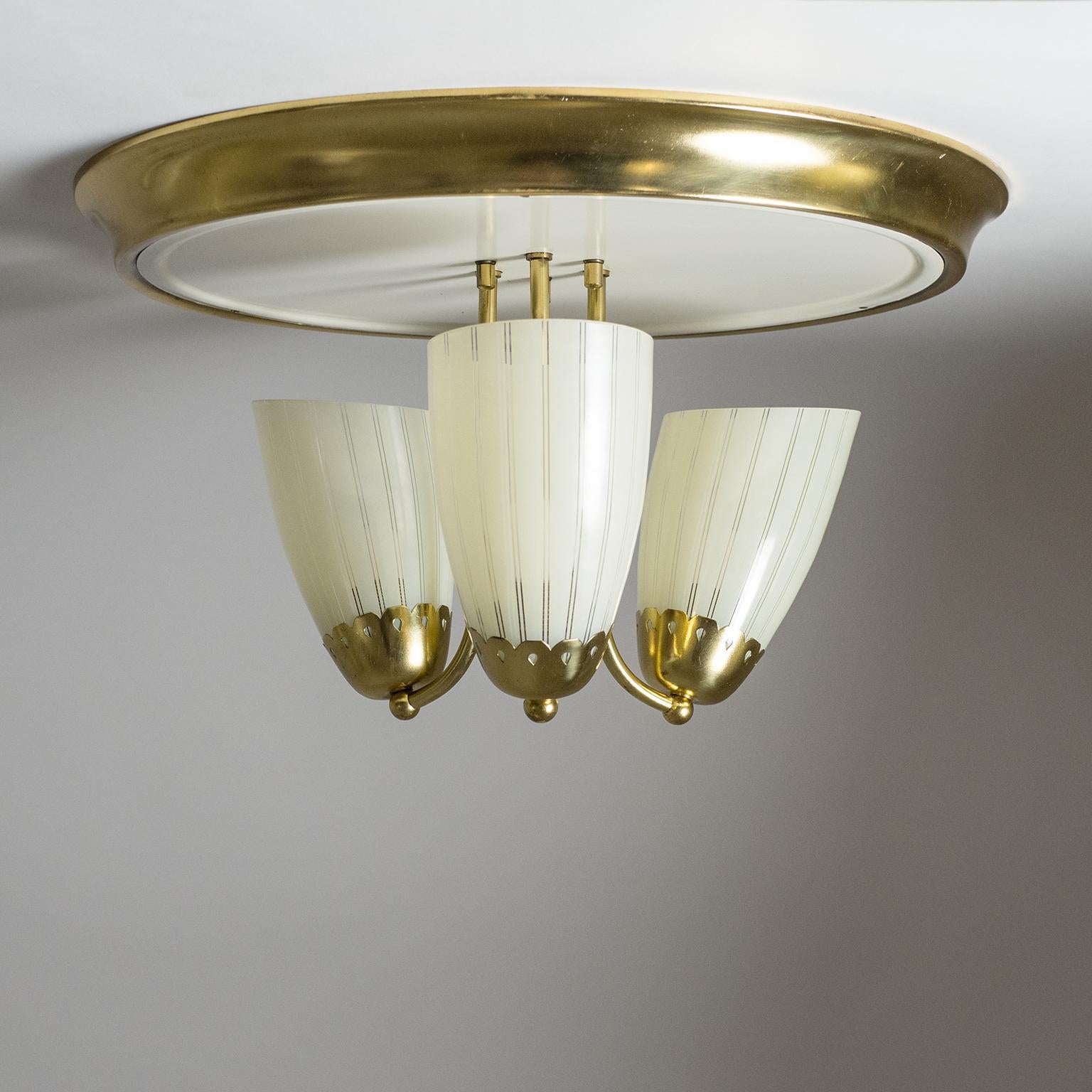 Lovely large brass and glass flush mount from the 1950s. Underneath a large brass and off-white lacquered backplate are three blown glass diffusers with an ivory colored striped enameled decor. Very fine original condition with a light patina on the