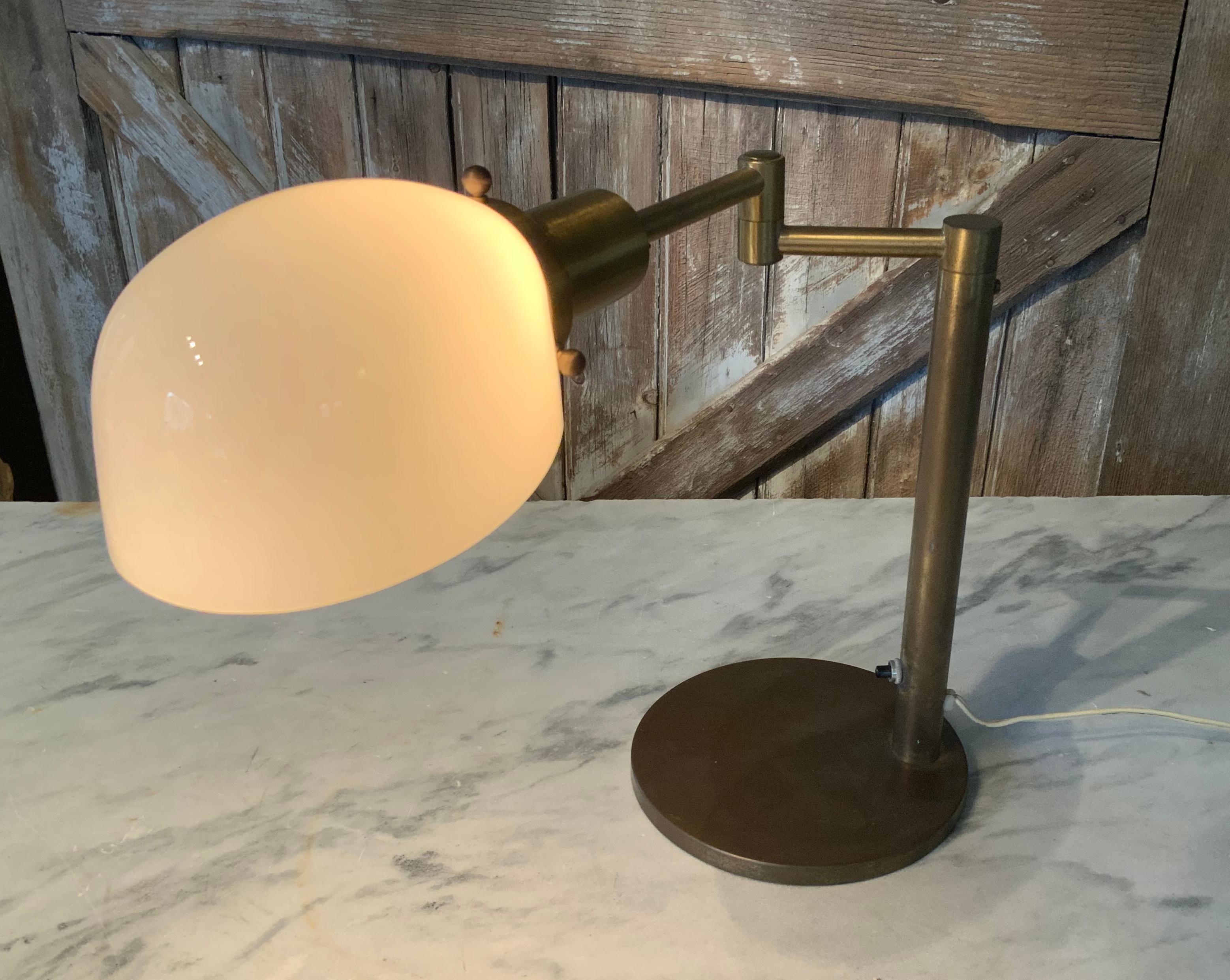 A beautiful and classic modern brass swing arm desk lamp by Walter Nessen. very handsome design and with the original opaline glass shade. Stamped Nessen Lighting NYC.