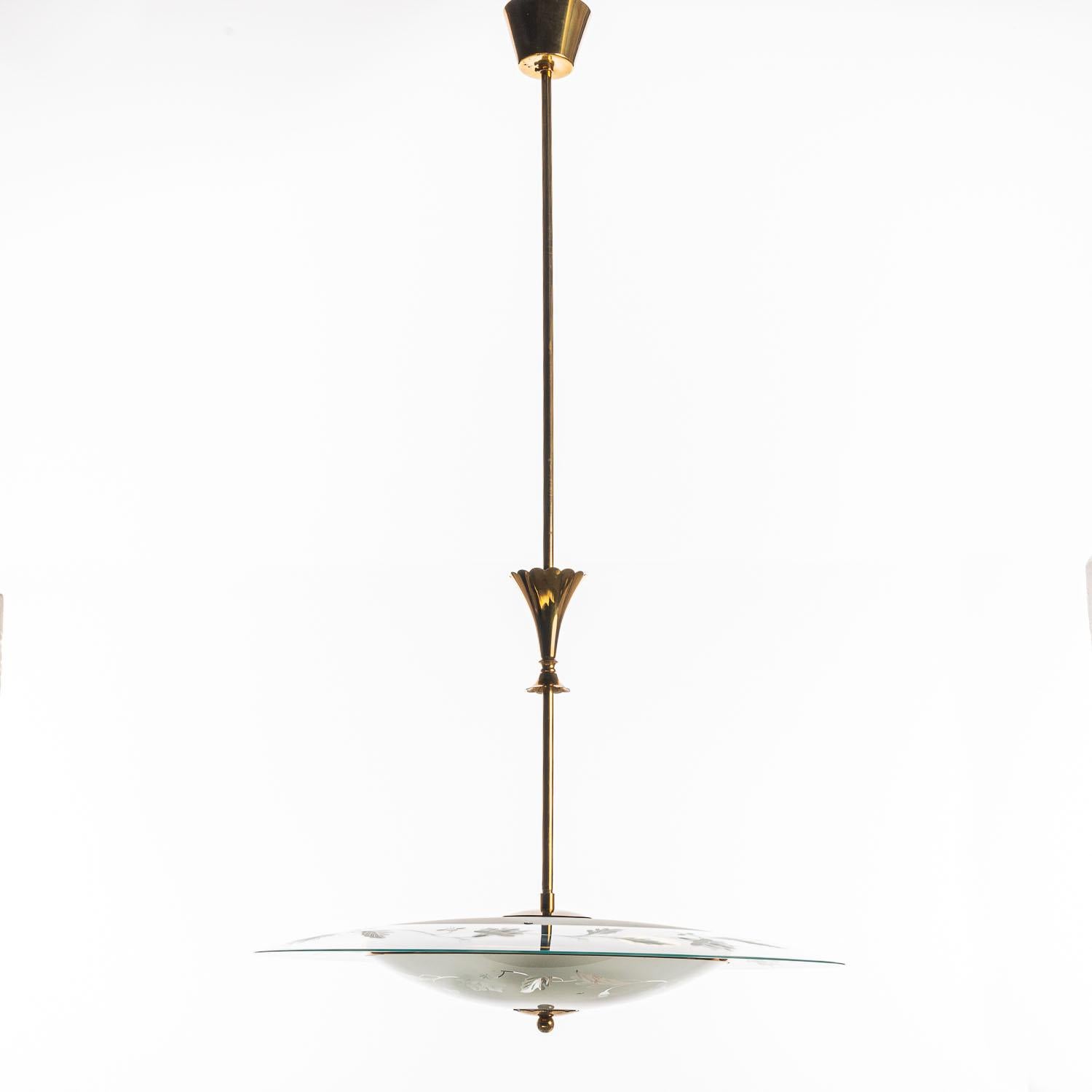 Cette élégante lampe se compose d'un cadre en laiton et de deux réflecteurs/sauceurs en verre uniques. 
Le réflecteur rond inférieur en verre incurvé avec des motifs floraux est monté sous un réflecteur rond plus grand en verre gravé et