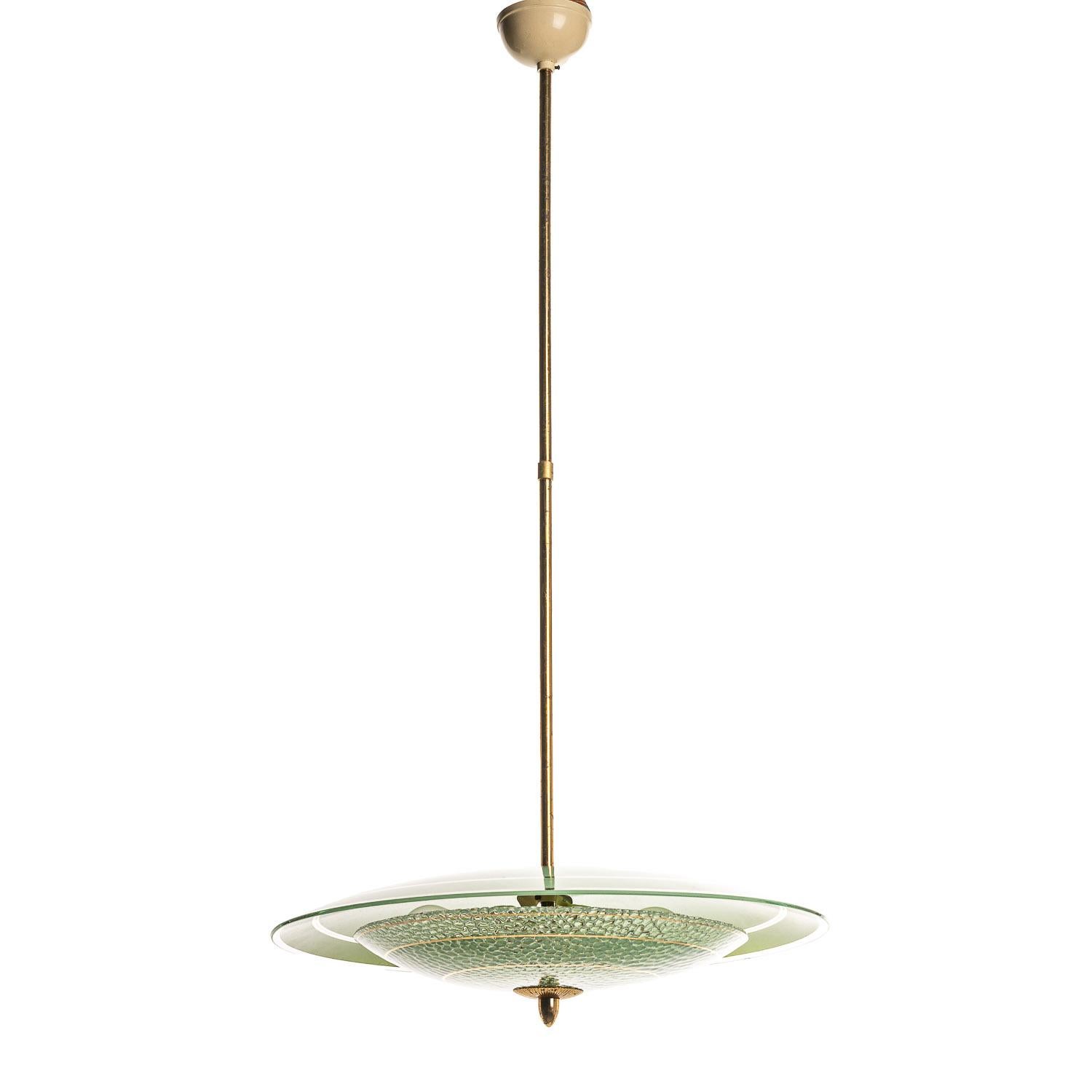 This playful piece consists of a brass frame connecting two unique frosted glass reflectors in green. 
The lower glass reflector has a bubble-texture and is accented with gold-colored rings. This mounts underneath a round, green frosted glass