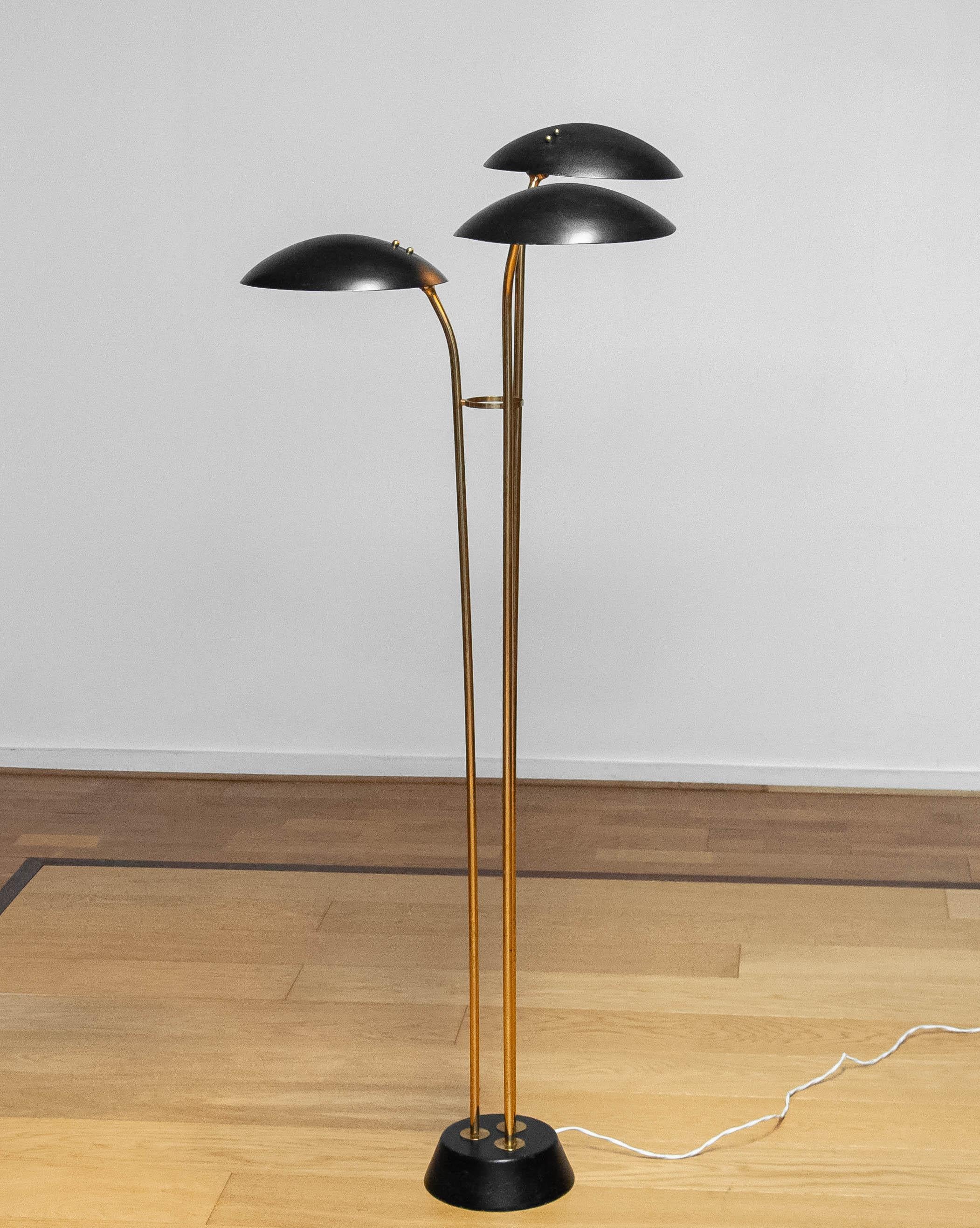 Schöne und sehr seltene Stehlampe aus Messing mit drei schwarz lackierten Metallschuppenschirmen ( Modell: 74585 ), hergestellt von den Brüdern Malmström für Bröderna Malmströms metallvarufabrik in Malmö in Schweden in den 1950er Jahren. 
Die