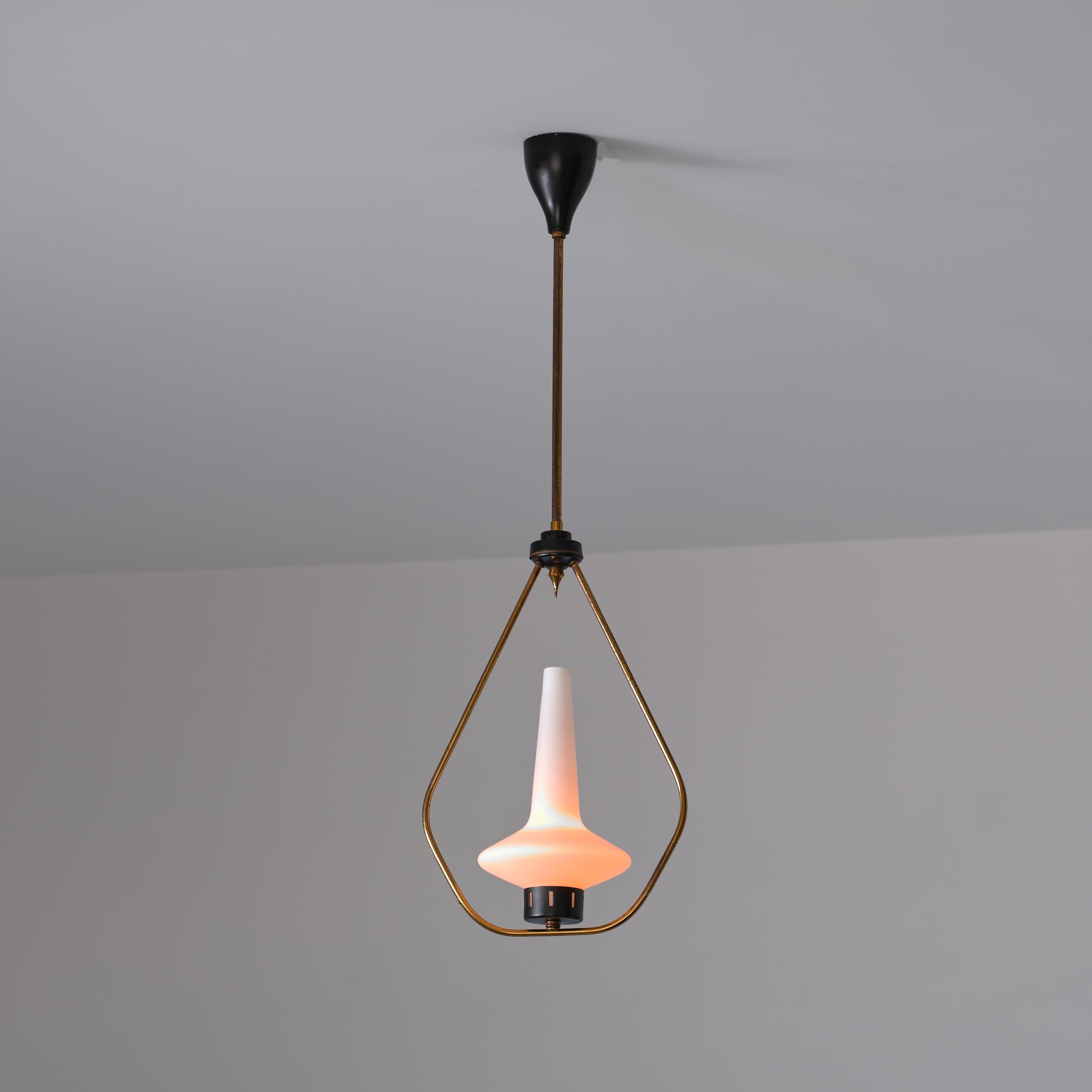Lampada a sospensione degli anni '50 con struttura a goccia in ottone che racchiude uno scultoreo paralume in vetro opalino. Il paralume è inserito in un supporto smaltato scuro ed è sospeso a una bacchetta d'ottone dritta con un baldacchino da