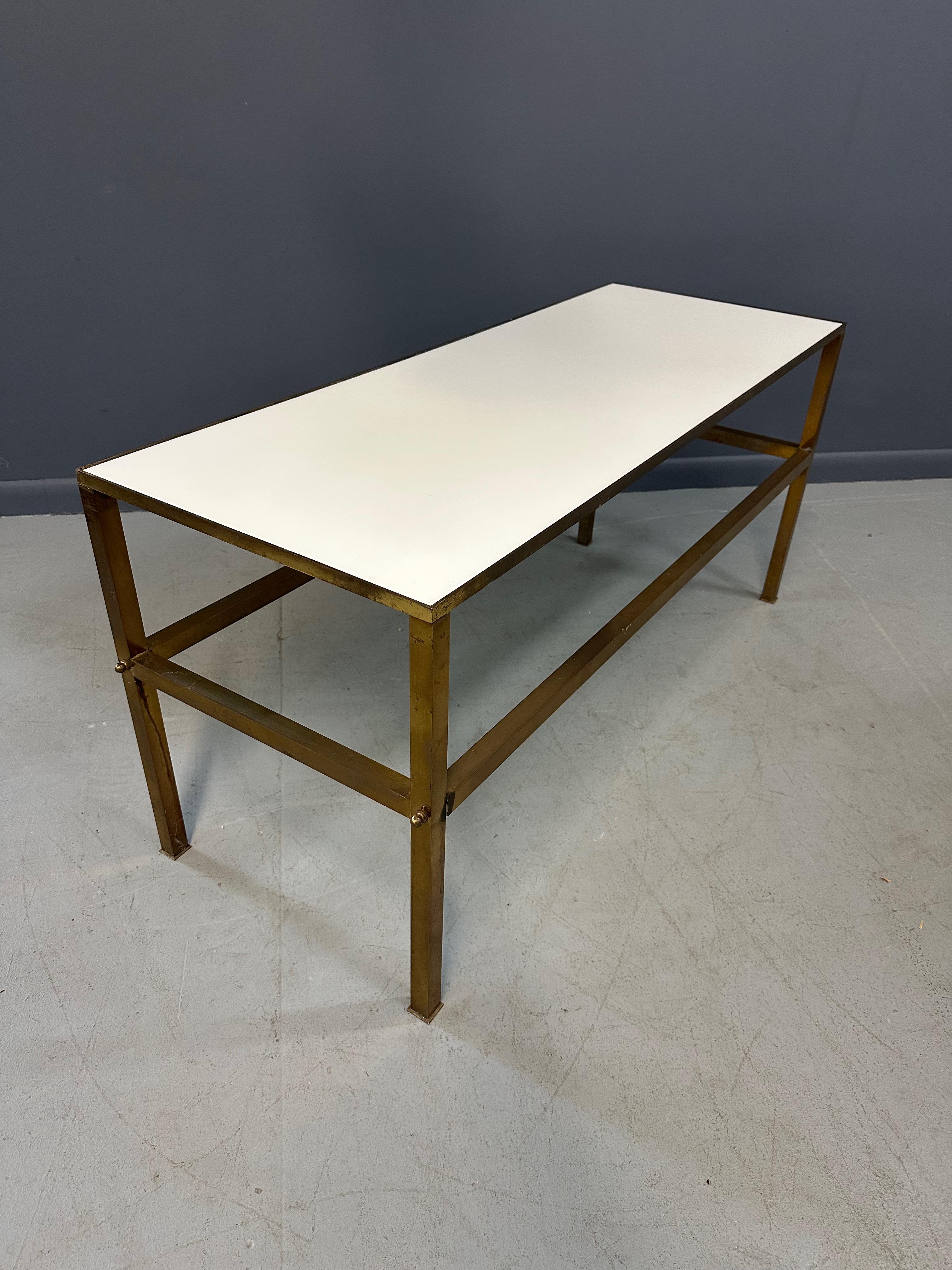 Enhance your living space with this vintage 1950s Brass Console Table. The elegant brass frame and Vitrolite white top provide a sleek surface for displaying decor items or serving as a TV or entertainment spot. The perfect addition to any modern or
