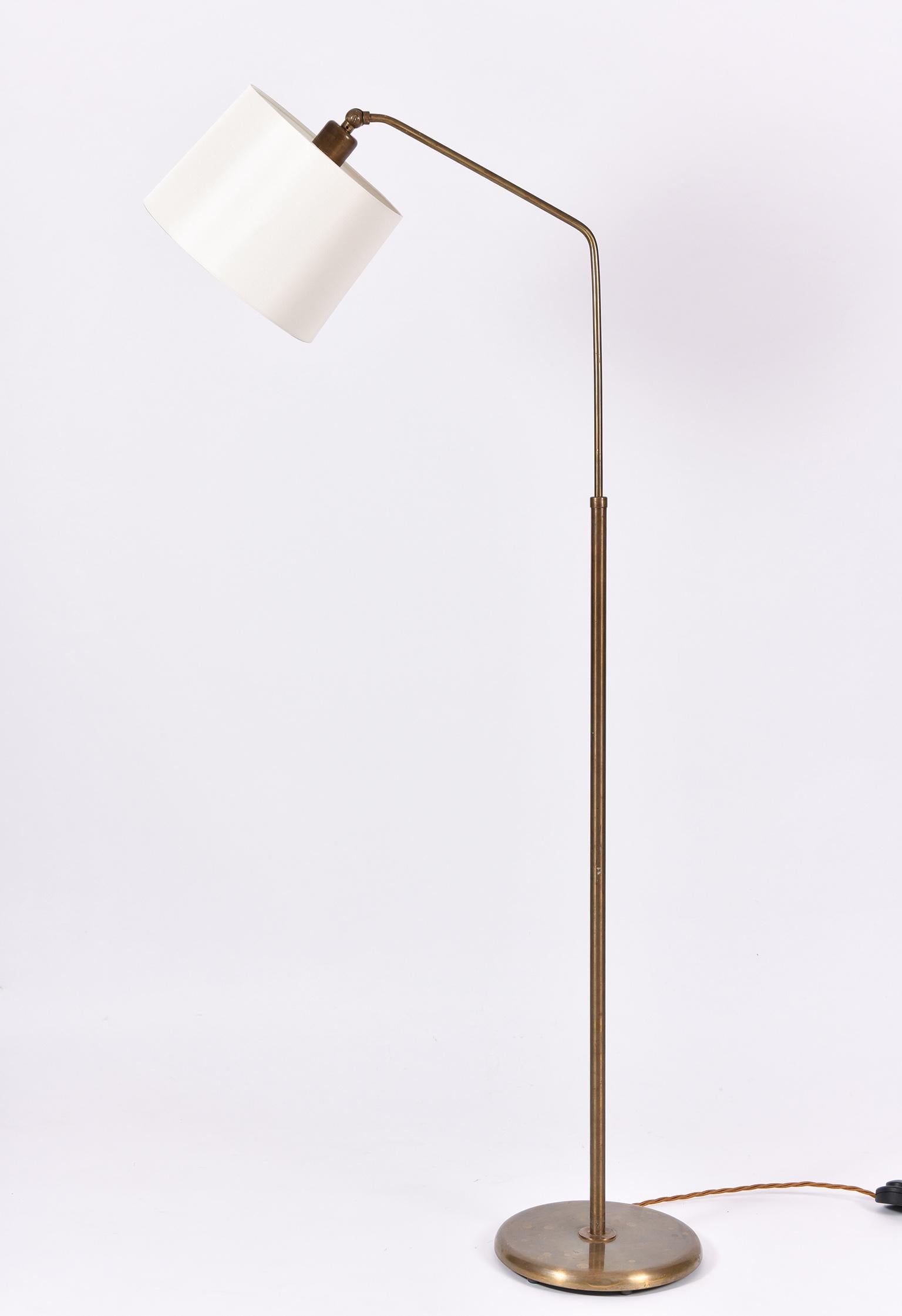 A patinated brass floor lamp, with an ivory fabric shade.
France, circa 1950.