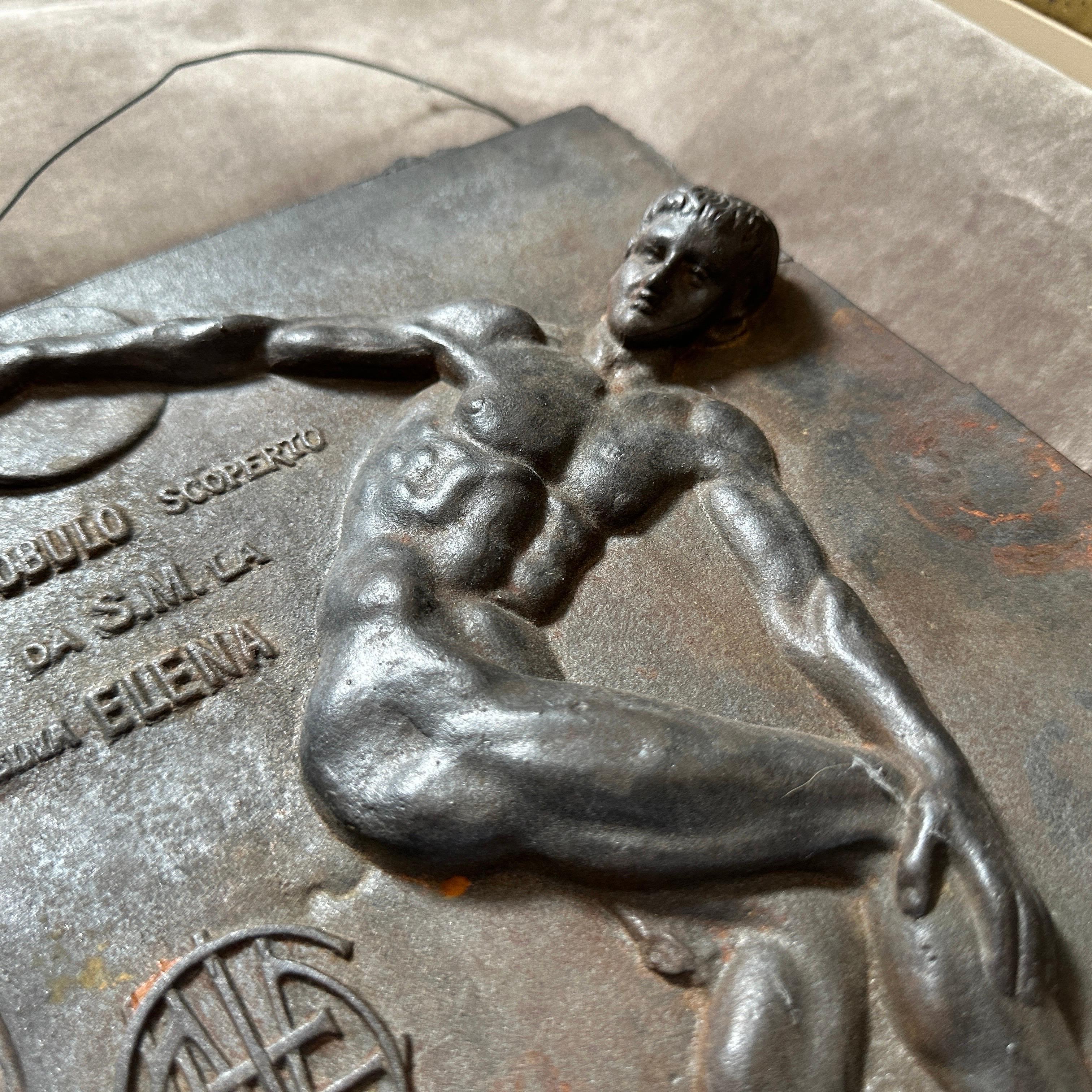 El panel de bronce representa a un lanzador de disco, captando un momento dinámico de atletismo. Está inspirado en la antigua estatua griega 