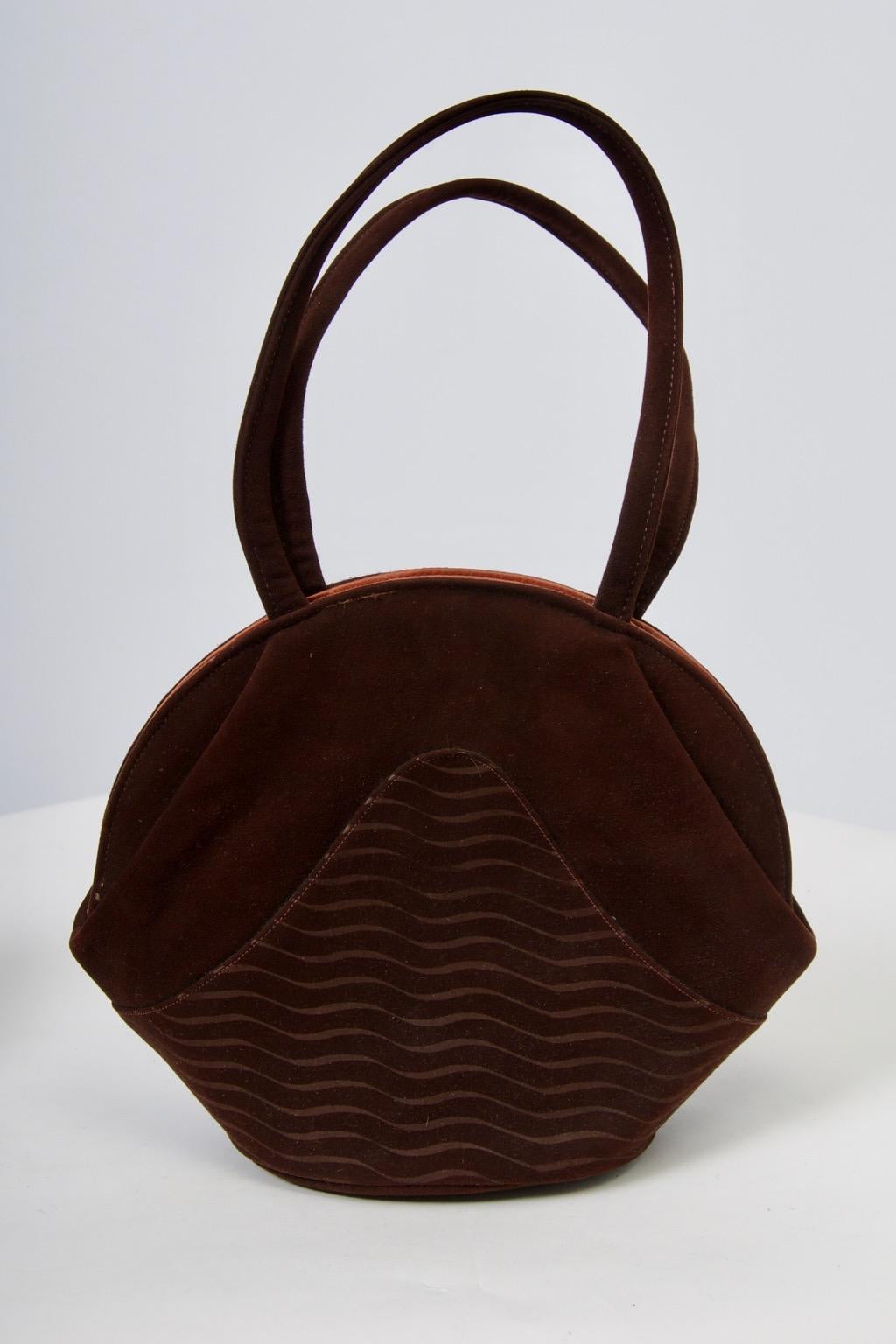 1950s brown suede handbag and matching slingback, open toe pumps in brown suede, both decorated with a carved wave pattern. The unusually shaped handbag sports a double handle and snaps open and closed to reveal a copper-colored satin lining with
