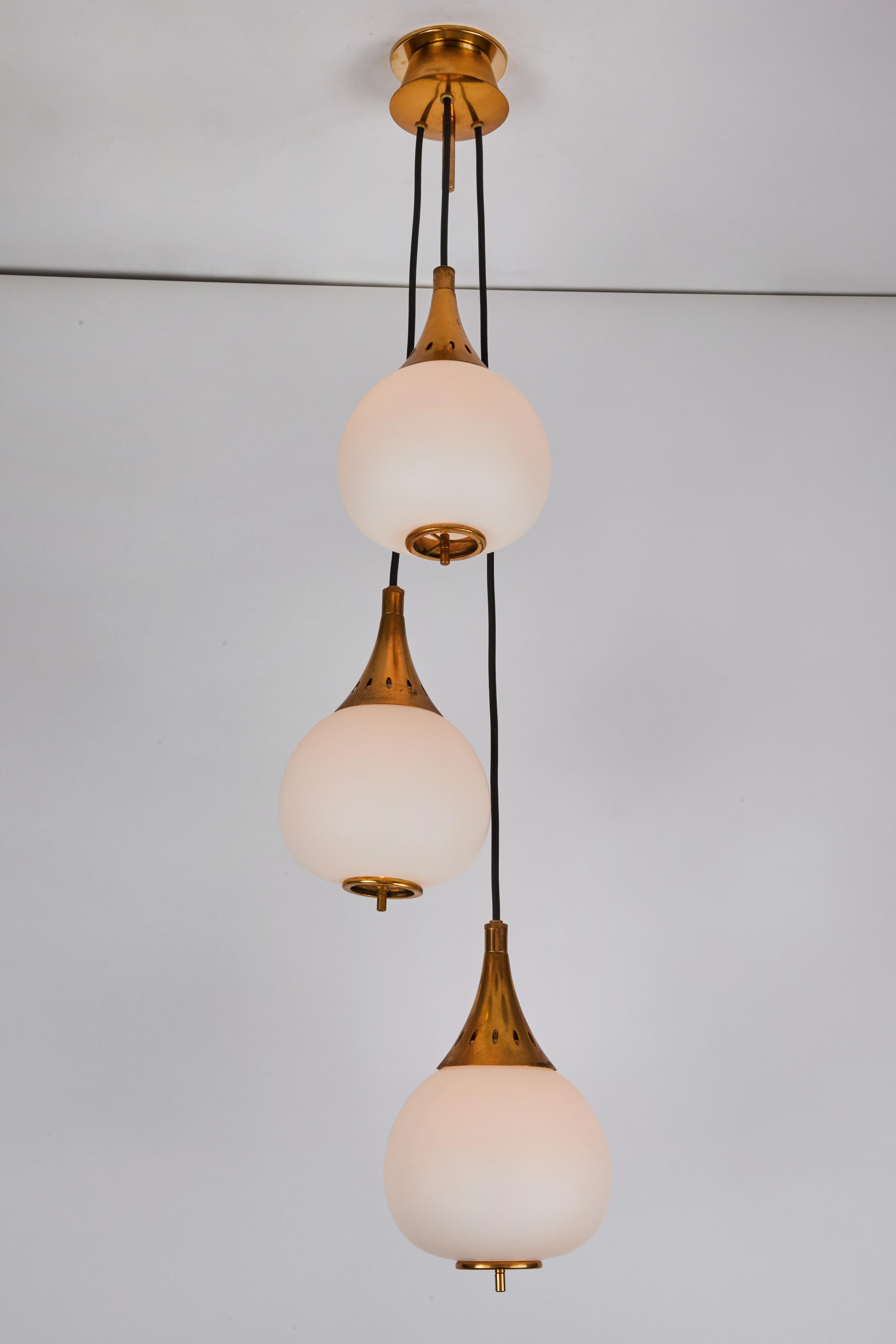 1950s Bruno Gatta brass and glass chandelier for Stilnovo. A quintessentially 1950s Italian design executed in three cascading matte finish opaline glass pendants with sculptural brass hardware and the original architectural ceiling canopy modified