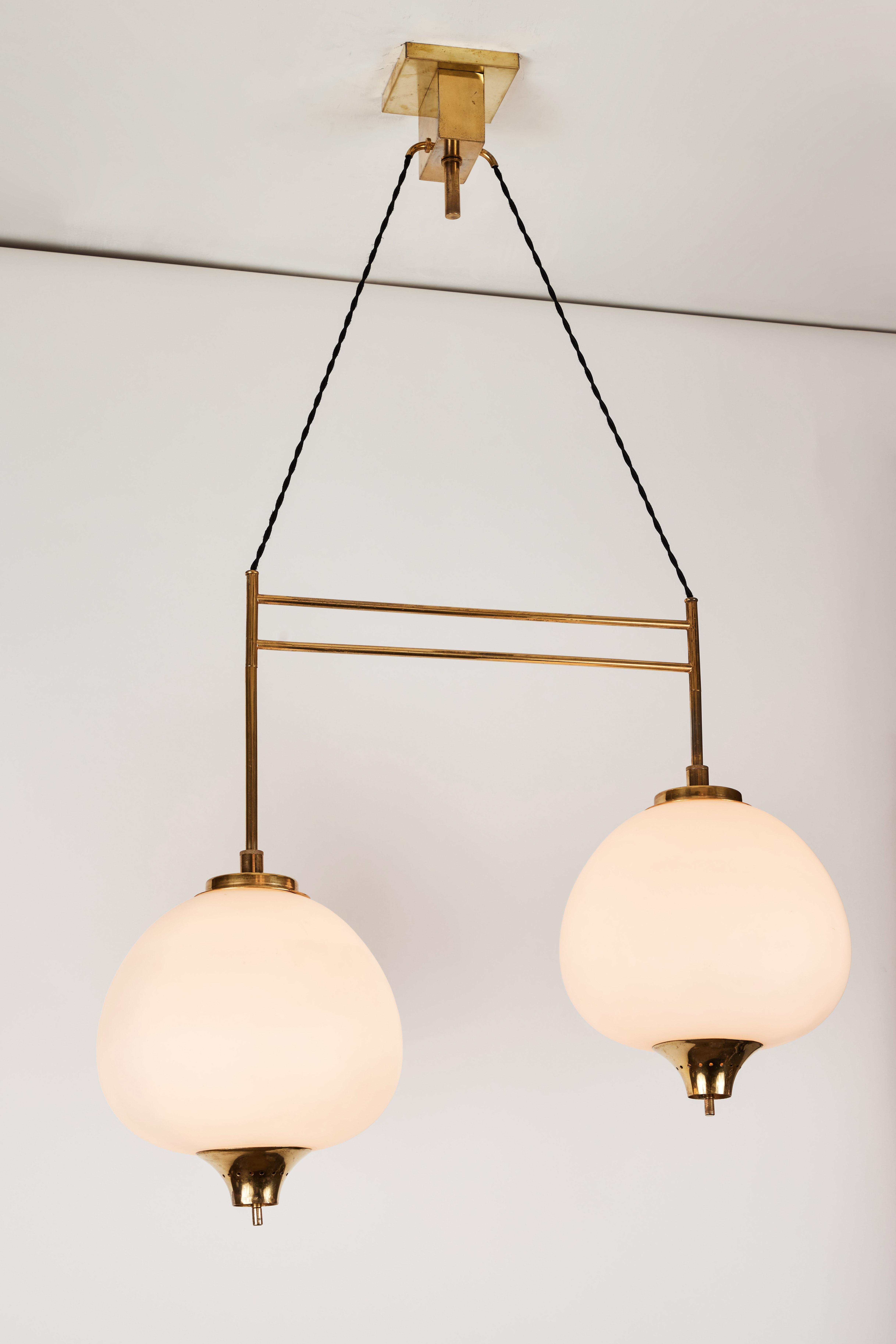 1950s Bruno Chiarini double pendant suspension lamp for Stilnovo. A quintessentially 1950s Italian design executed in two cascading matte finish opaline glass pendants with sculptural brass hardware and the original architectural ceiling canopy