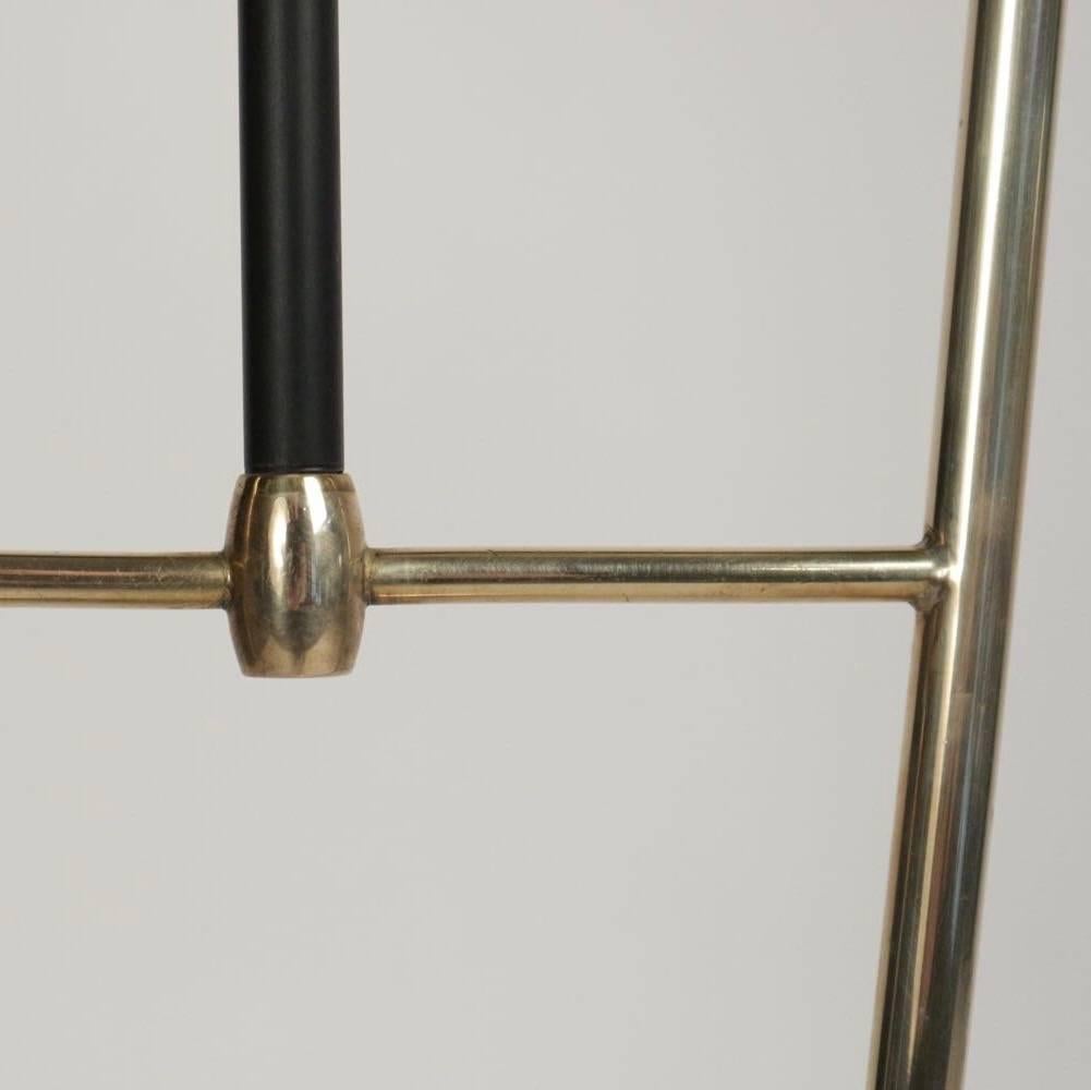 1950s buckle floor lamp by Maison Lunel.
Consisting of two golden brass rods laid on a round base and surmounted by custom off-white lampshades. A third blackened brass suspended rod is decorated on the upper part by a buckle that highlights the
