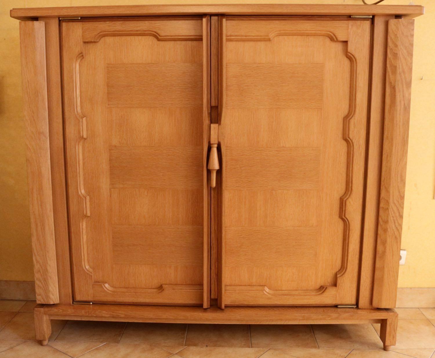 Natural oak cabinet or small dresser. Two carved front doors are opening on oak shelves. Two side doors are opening on shelves. An ergonomic handle is actioning a rack mechanism to lock and unlock the doors.
The cabinet stand on four oak
