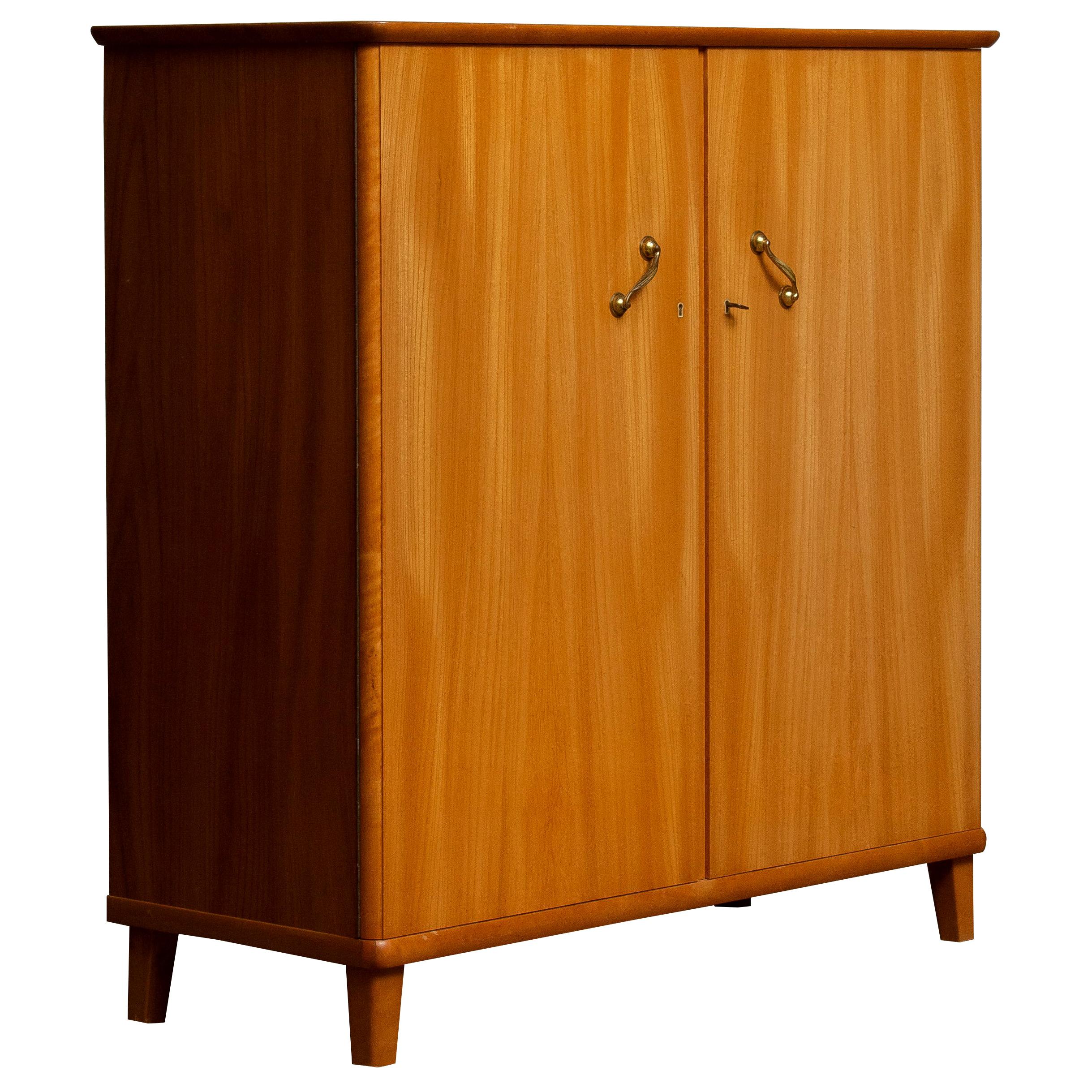 Beautiful cabinet in elm made in Tibro, Sweden.

This cupboard is made up of two front swing doors that can be locked with on the right side two internal drawers and two in height-adjustable shelves. There are also two adjustable shelves on the
