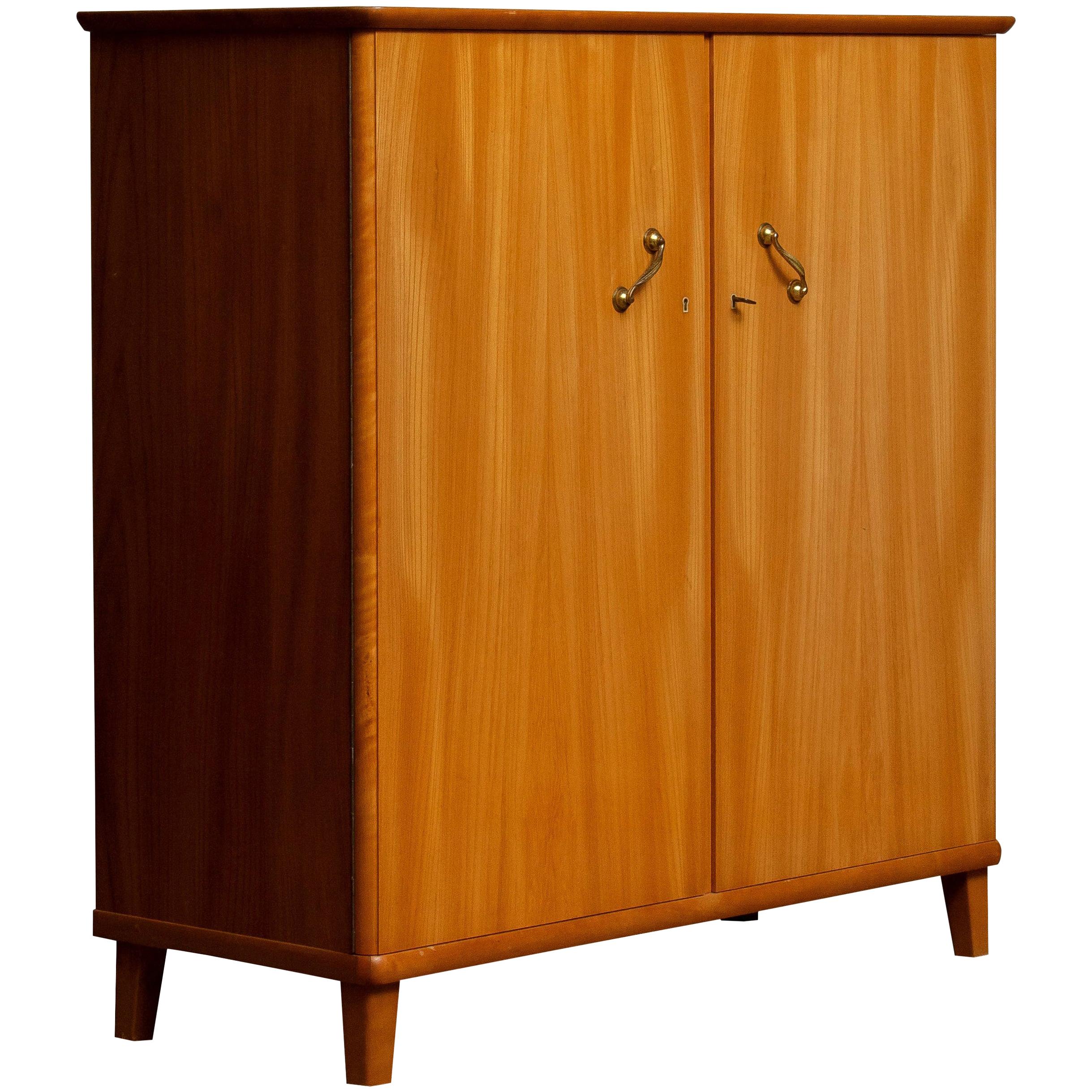 Beautiful cabinet in elm made in Tibro, Sweden.

This cupboard is made up of two front swing doors that can be locked with on the right side two internal drawers and two in height-adjustable shelves. There are also two adjustable shelves on the