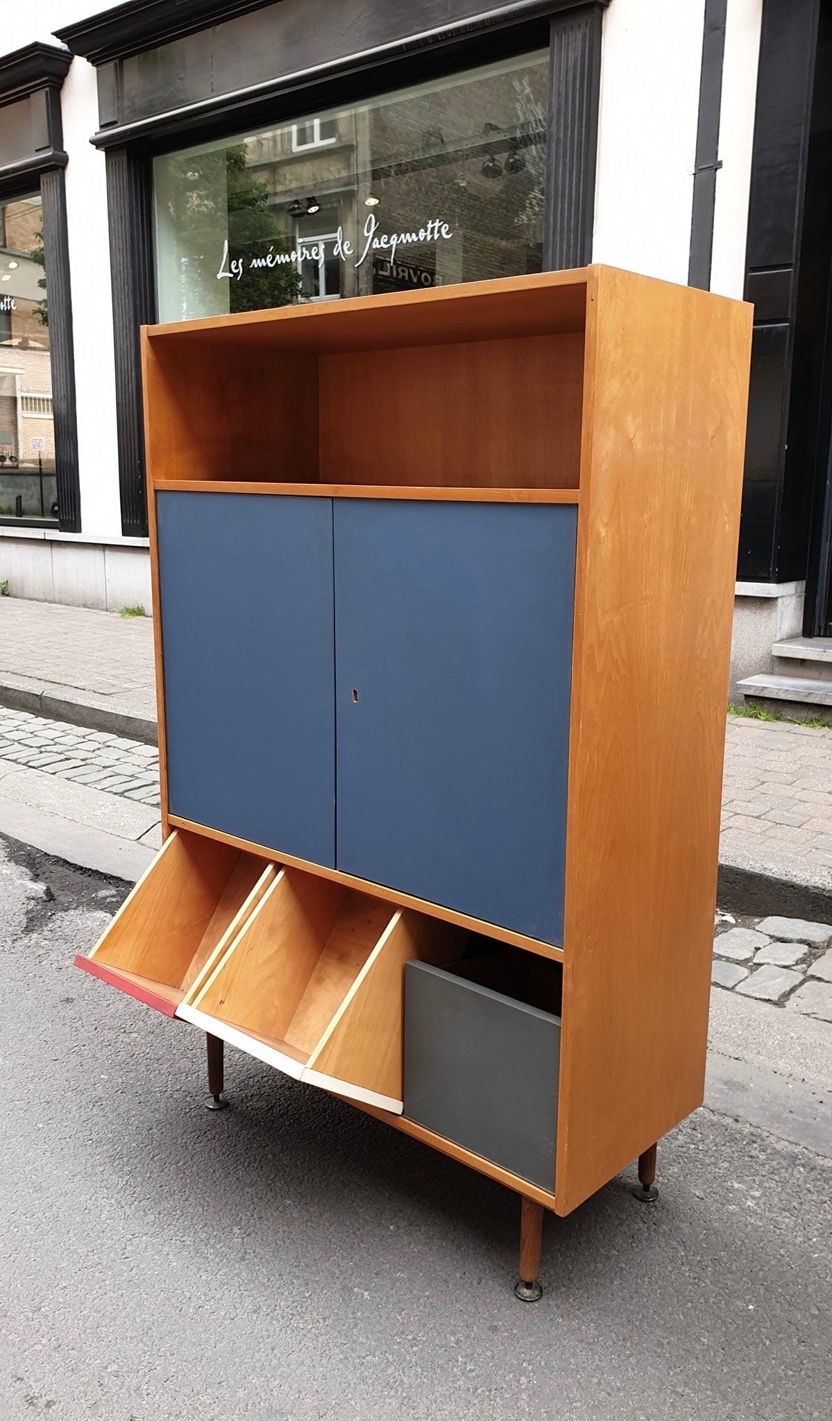 Originaler Schrank aus den 1950er Jahren mit blau gefärbten Türen und dreifarbigen Kipptüren in Birkenfurnier.
Oben befinden sich große Regale und die Türen werden mit dem Originalschlüssel geliefert.
Metallspitzen an den massiven