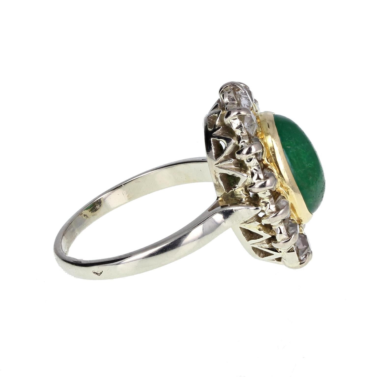 This wonderful 50's ring features a central oval emerald cabochon of deep green, surrounded in a golden, frilled frame and bordered with old mine-cut diamonds to form an oval cluster. Impressive and unusual. Shank and setting tests as 18 carat gold