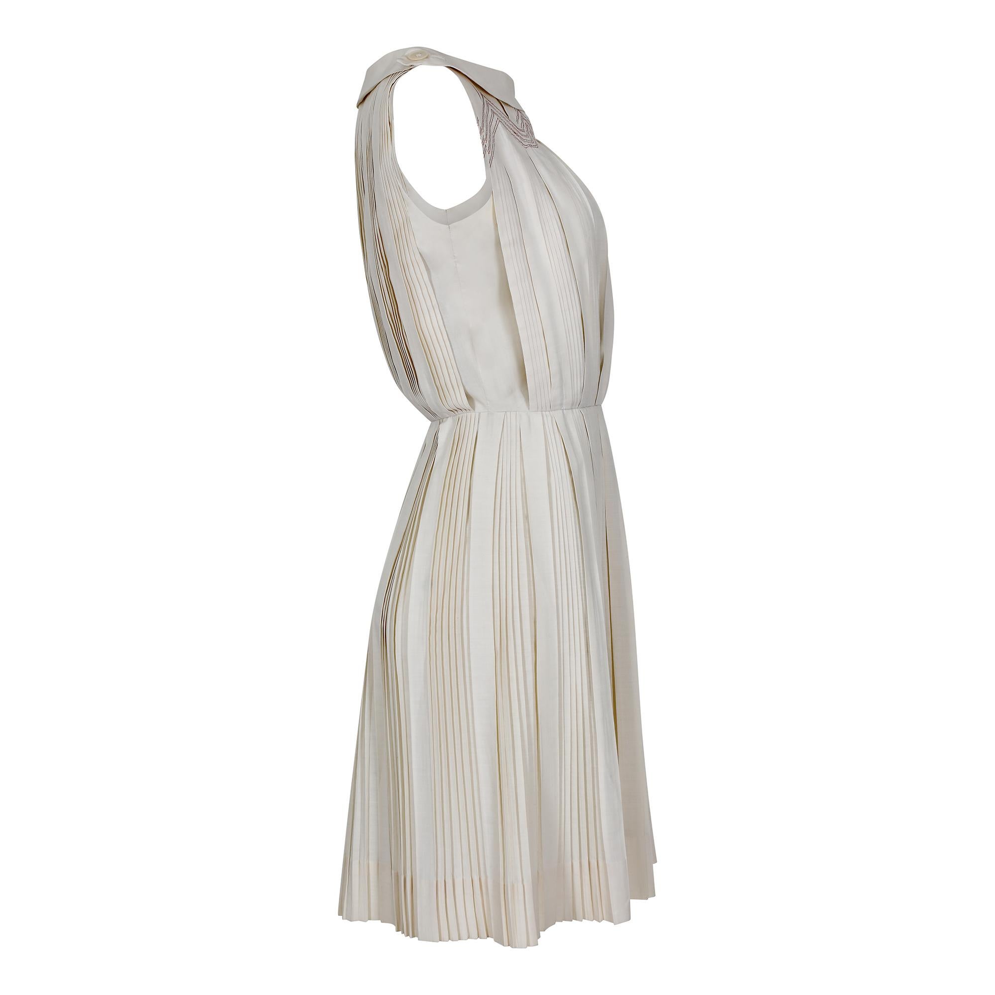 A classic example of good quality American day wear. We love this vintage label - Carlye pieces just ooze refinement. This creamy beige cotton knife pleat dress has an elegant scoop neck augmented with 2 pearlescent buttons.  These fasten on the