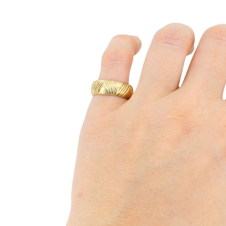 Cette bague Cartier des années 1950 est réalisée en or 14k et pèse 8 grammes. Il présente un design en or brossé avec un motif gravé de lignes entrecroisées qui s'enroule autour de la bande. La texture crée un contraste entre les finitions polies et