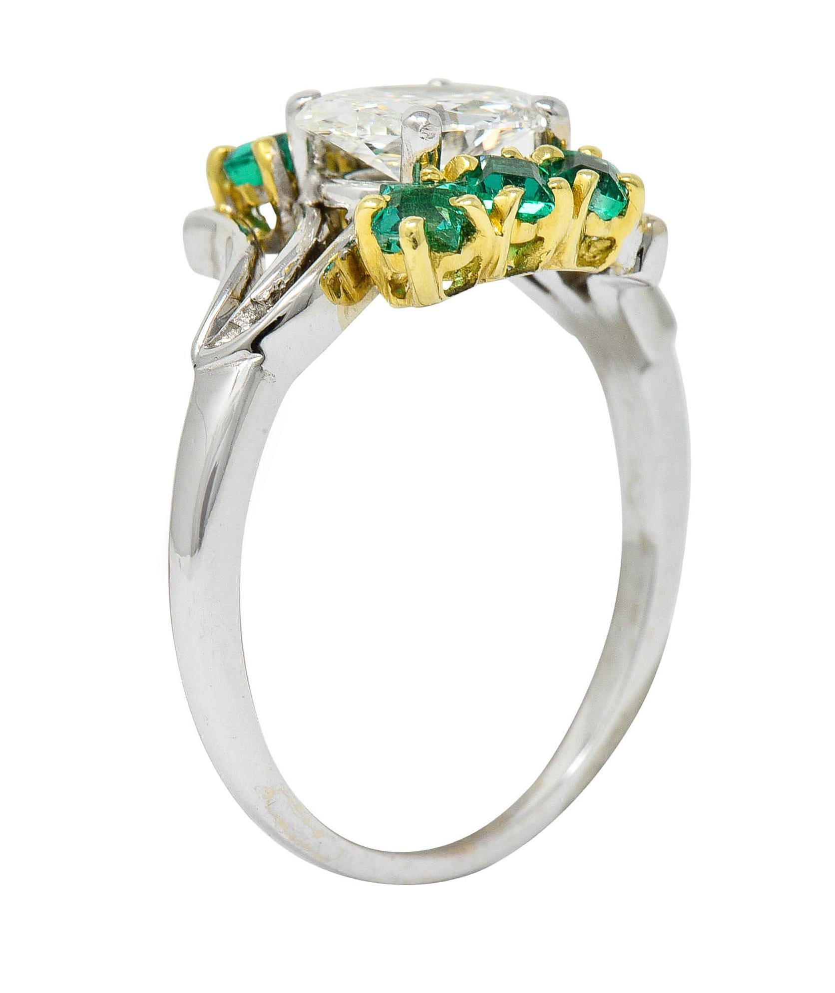Bypass style ring centers an oval brilliant cut diamond weighing 1.16 carat - I color with VS1 clarity

Set East to West and flanked by rectangular cut emeralds weighing in total approximately 0.60 carat

Set in yellow gold with well matched vibrant