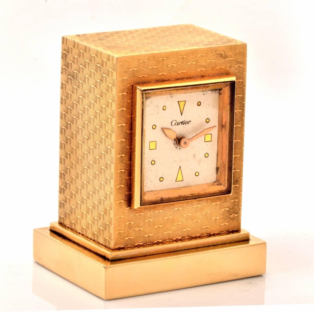 This aesthetically captivating authentic circa 1950 Cartier eight-day desk clock is made with a solid 14K yellow gold case. It is rendered in artfully textured gold, adding a glittering aspect to the case. The white dial features arrow hands and is