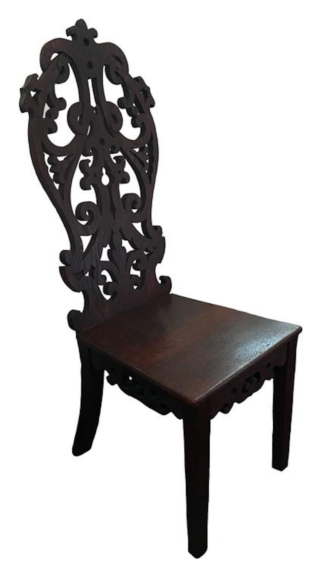 Pair of 1950s Haitian carved wood chairs. Hand-carved from a native hardwood. Elaborate carved seat back. 
Commissioned by American diplomats in 1957, while living outside of Port-au-Prince. 