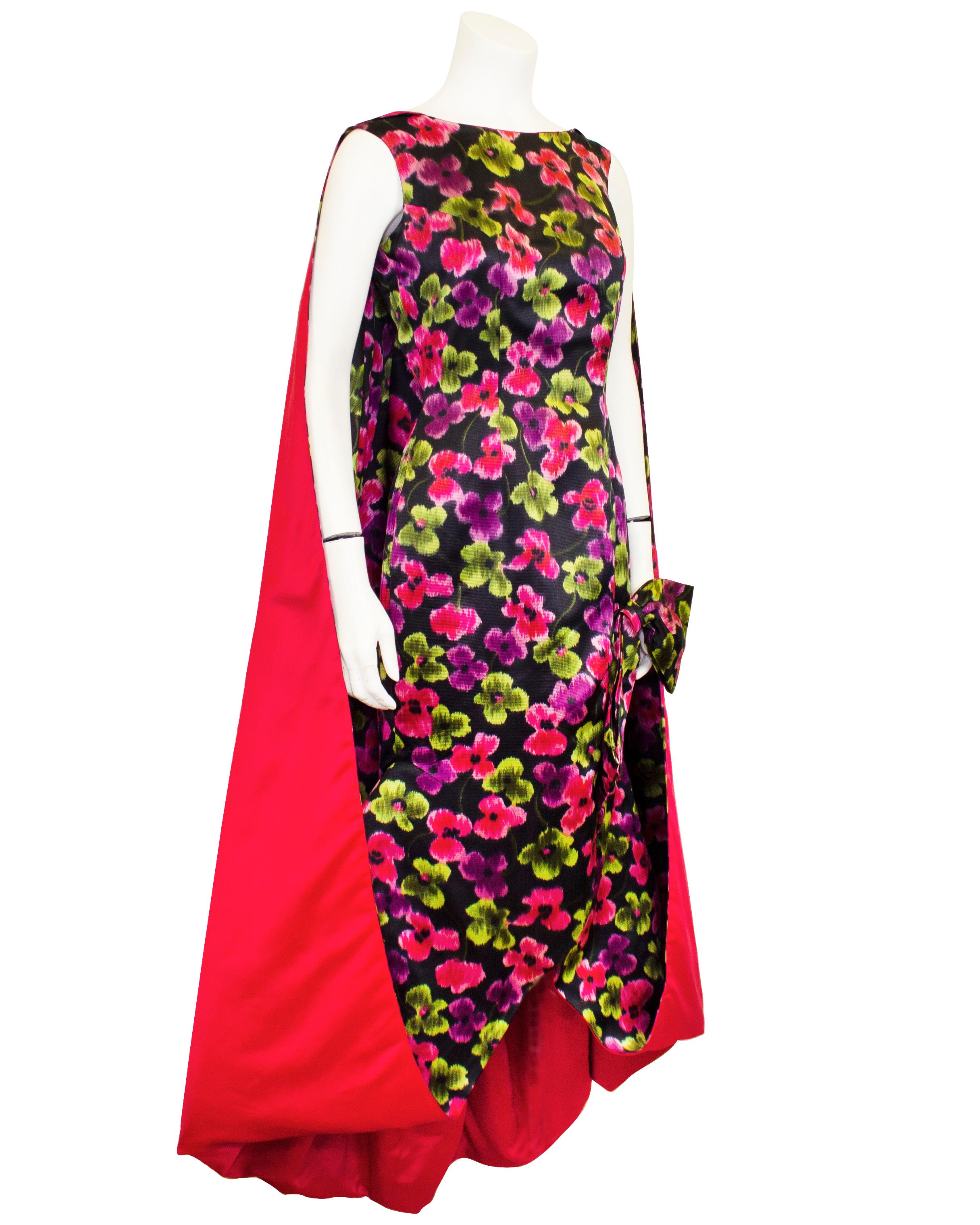 Dramatic and bright, this incredible Ceil Chapman evening dress from the 1950s has it all: drama, draping, Hi-low hemline, flattering capped sleeve, fitted shape with appliqué bow, contrasting lining and attached cape in magenta satin.... red carpet