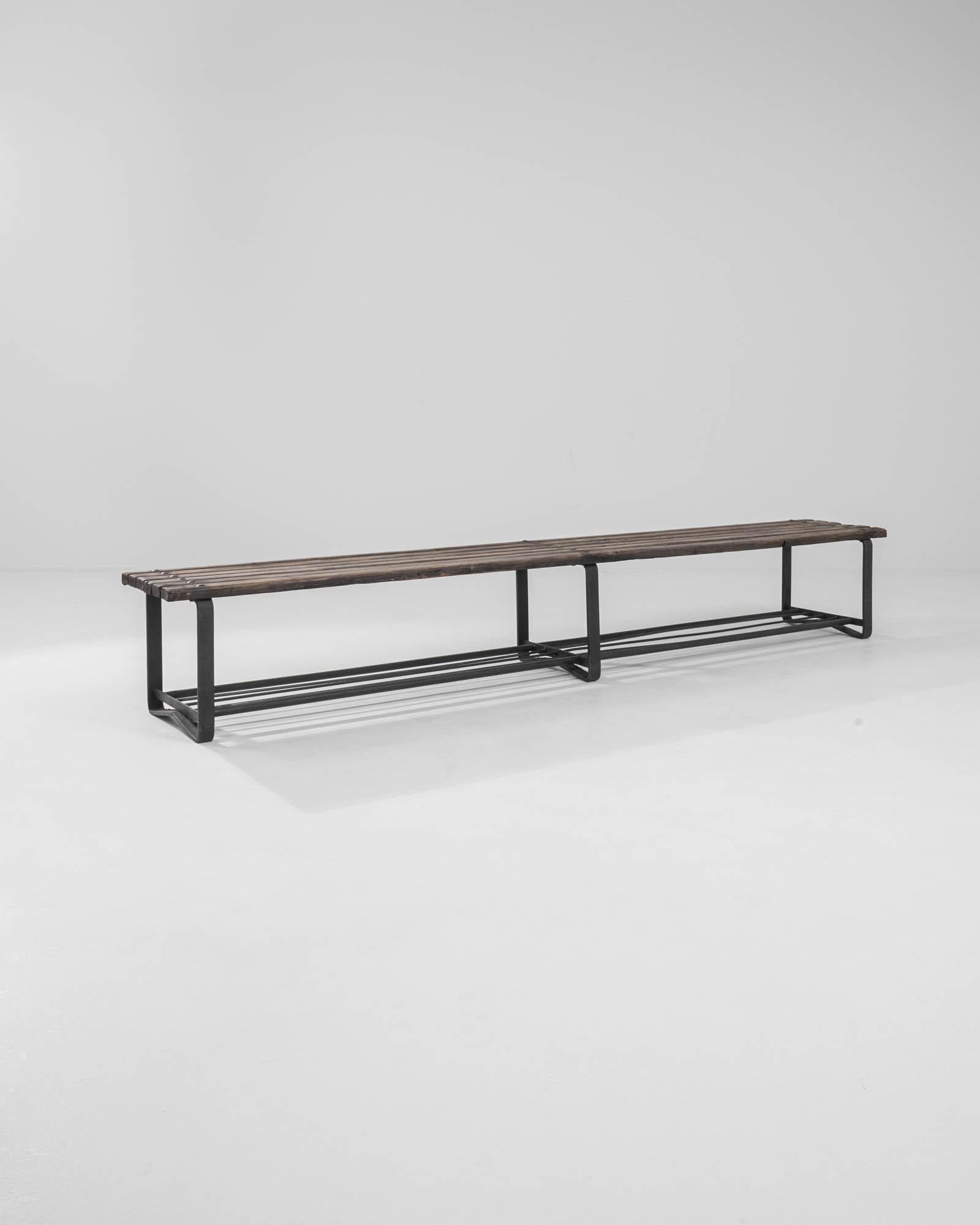 A sturdy steel and metal bench with minimalist industrial design manufactured in the Czech Republic, circa 1950s. Thick wooden slats show evidence of wear, a characteristic industrial patina, and are bolted to three steel frame supports. The