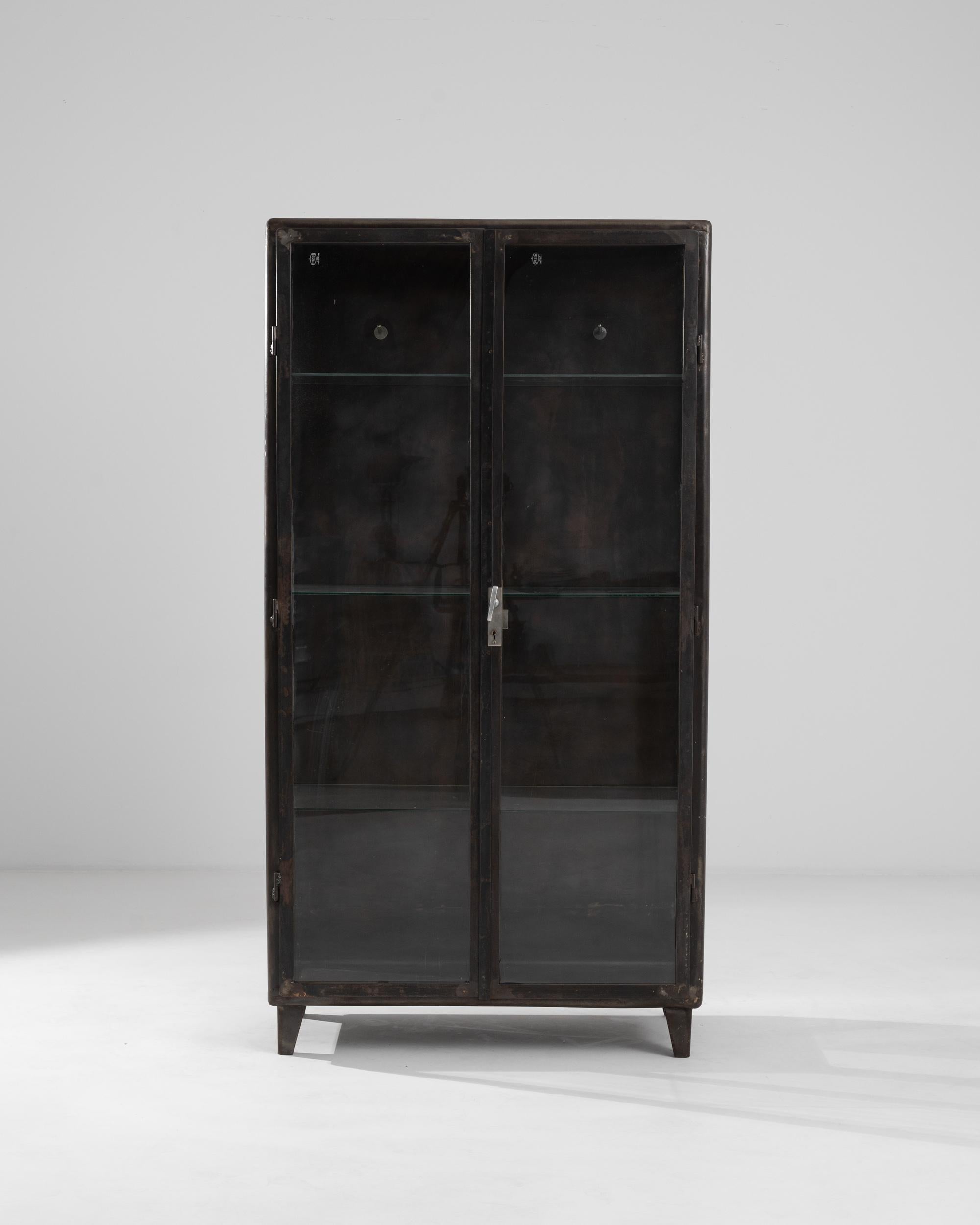 The 1950s Central European metal medical cabinet is a testament to the durability and elegance of industrial design. Its polished metal construction exudes a vintage charm that complements the minimalist aesthetic of modern interiors. Transparent